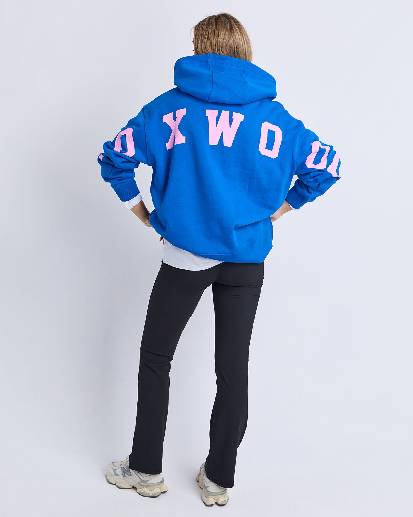Woman wearing a blue Foxwood hoodie with pink text on a white background