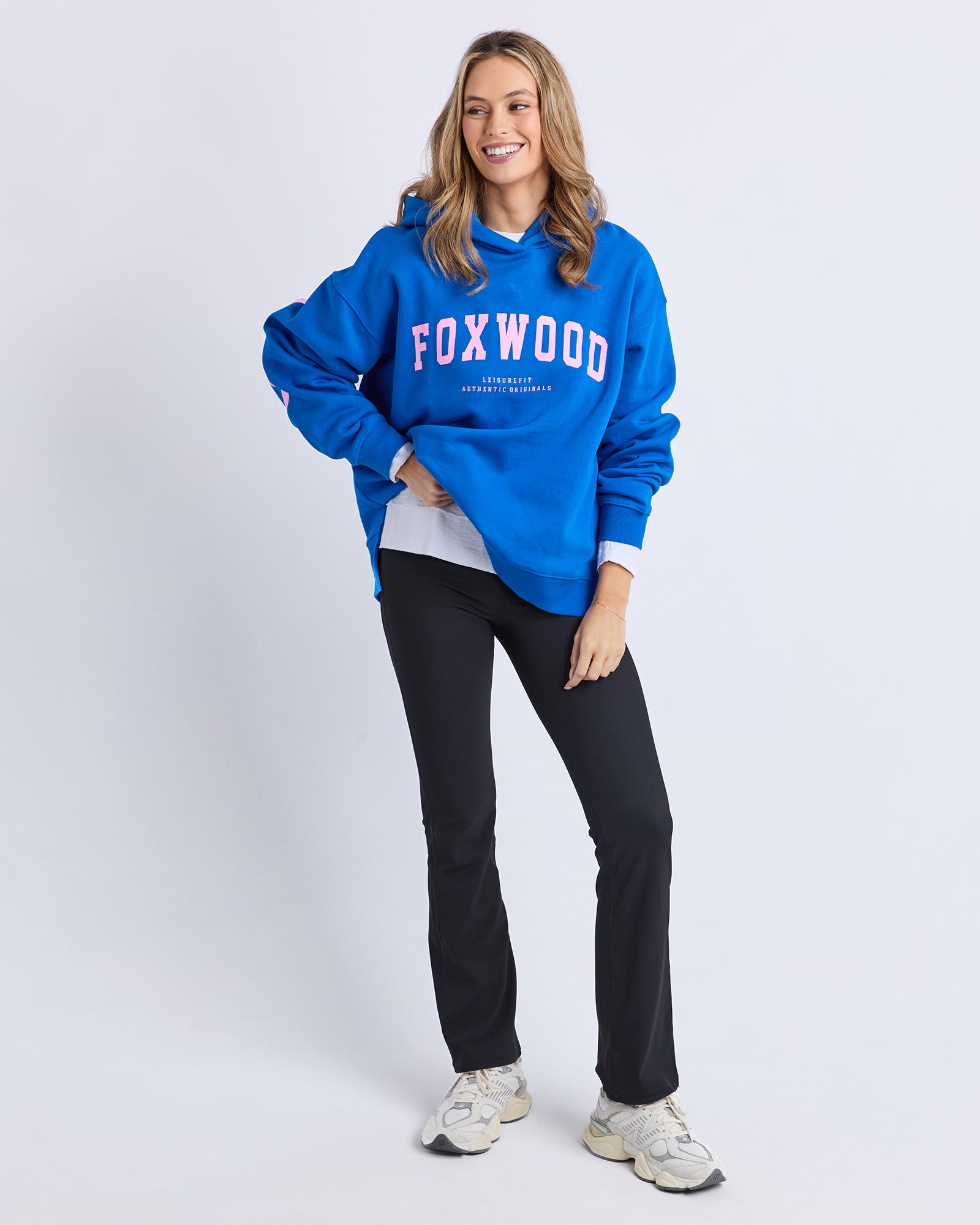 Image of Woman wearing a blue 'FOXWOOD' hoodie with pink print on a white background