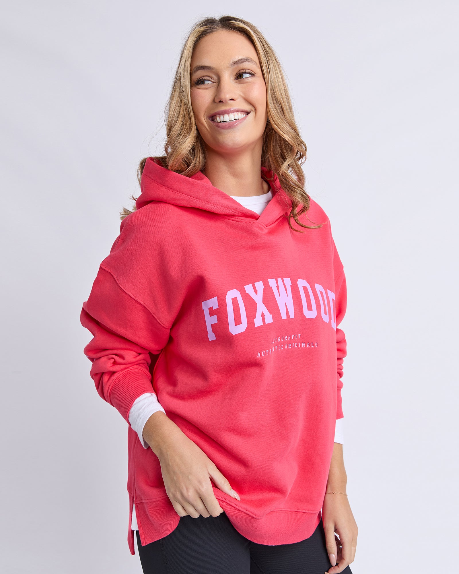 Woman wearing a raspberry hoodie with 'FOXWOOD' text in purple on a light grey background