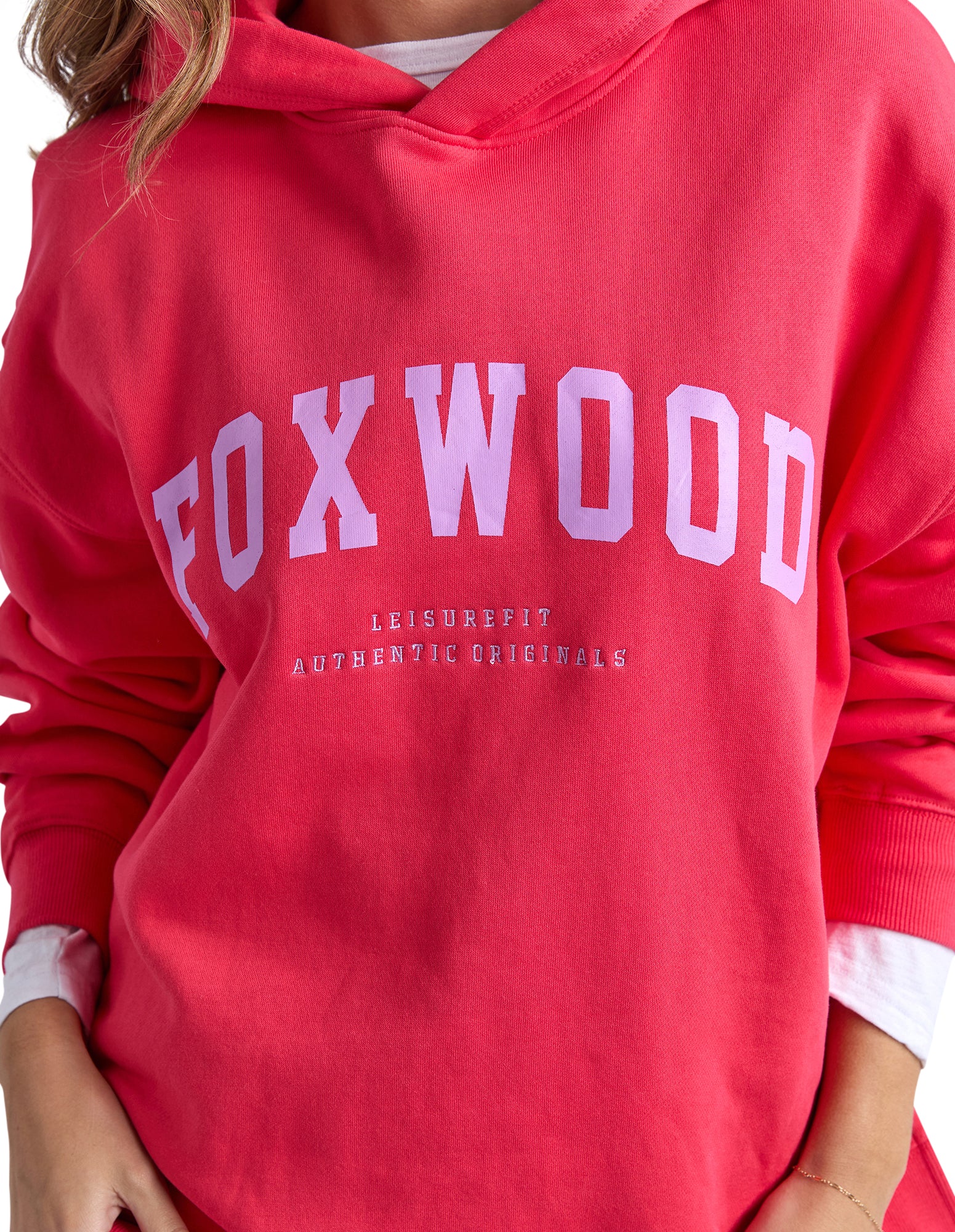 Image of Red hoodie with 'FOXWOOD' printed on it, worn by a woman.