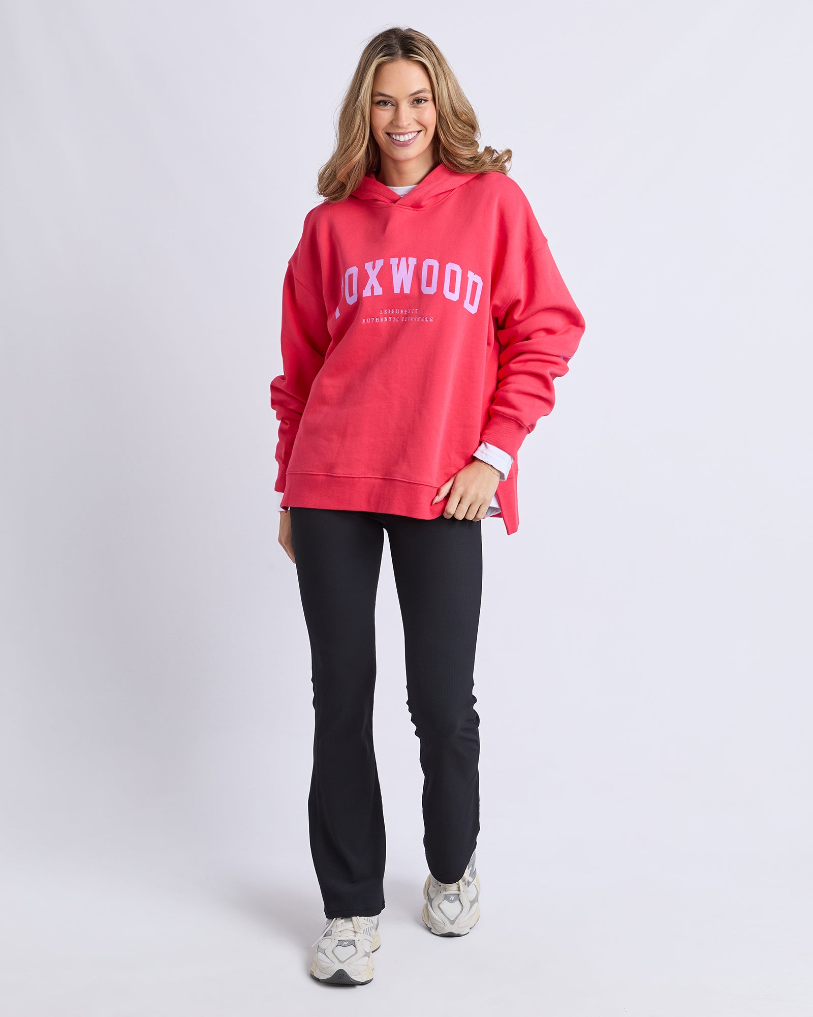 Image of Woman wearing a red 'FOXWOOD' hoodie and black pants on a white background