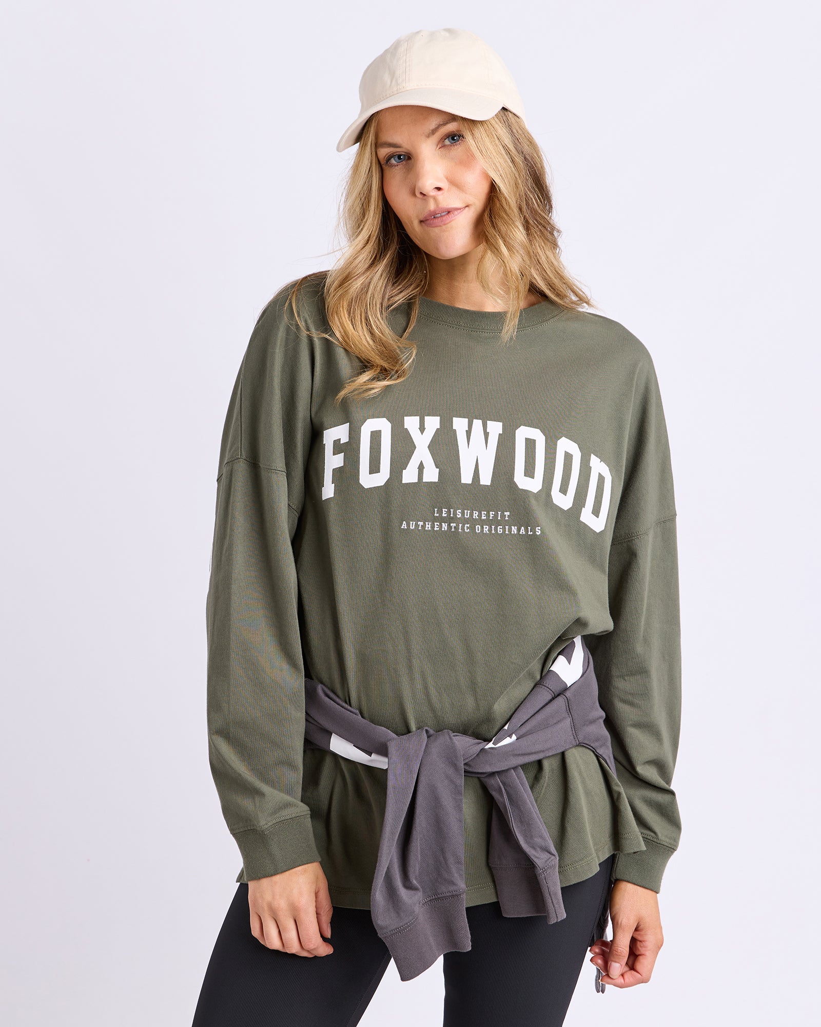 Woman wearing a khaki 'FOXWOOD' long sleeve tee against a white background