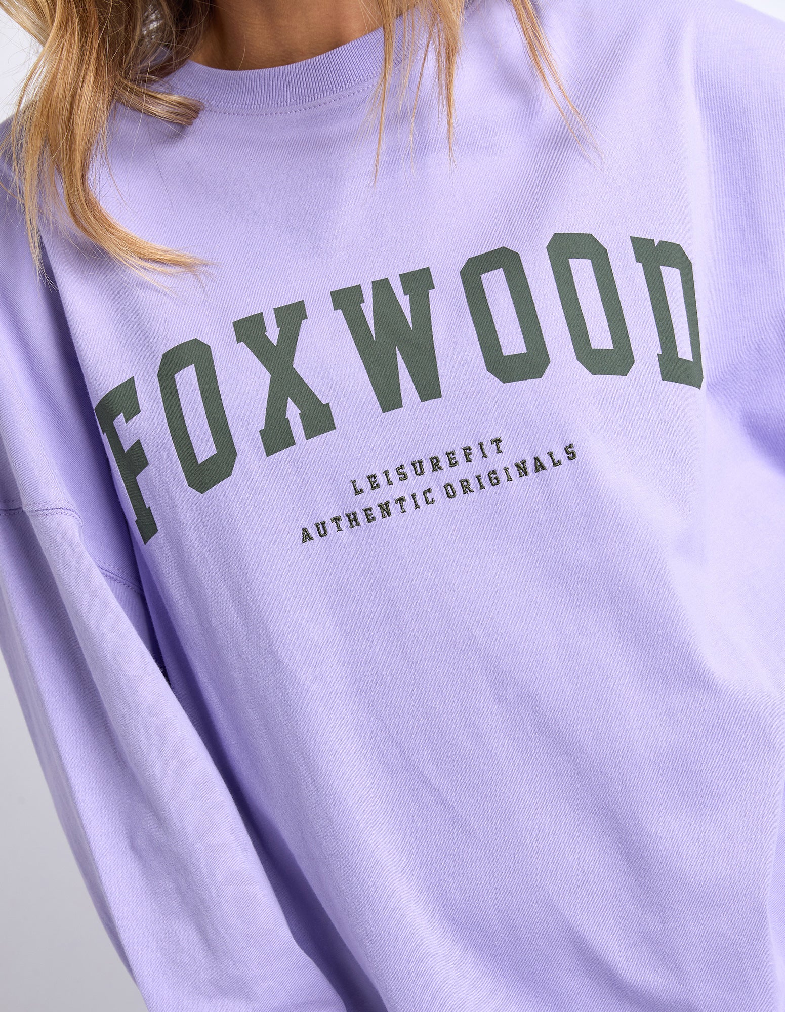 Light purple long sleeve tee with 'FOXWOOD' printed in khaki text on a plain background