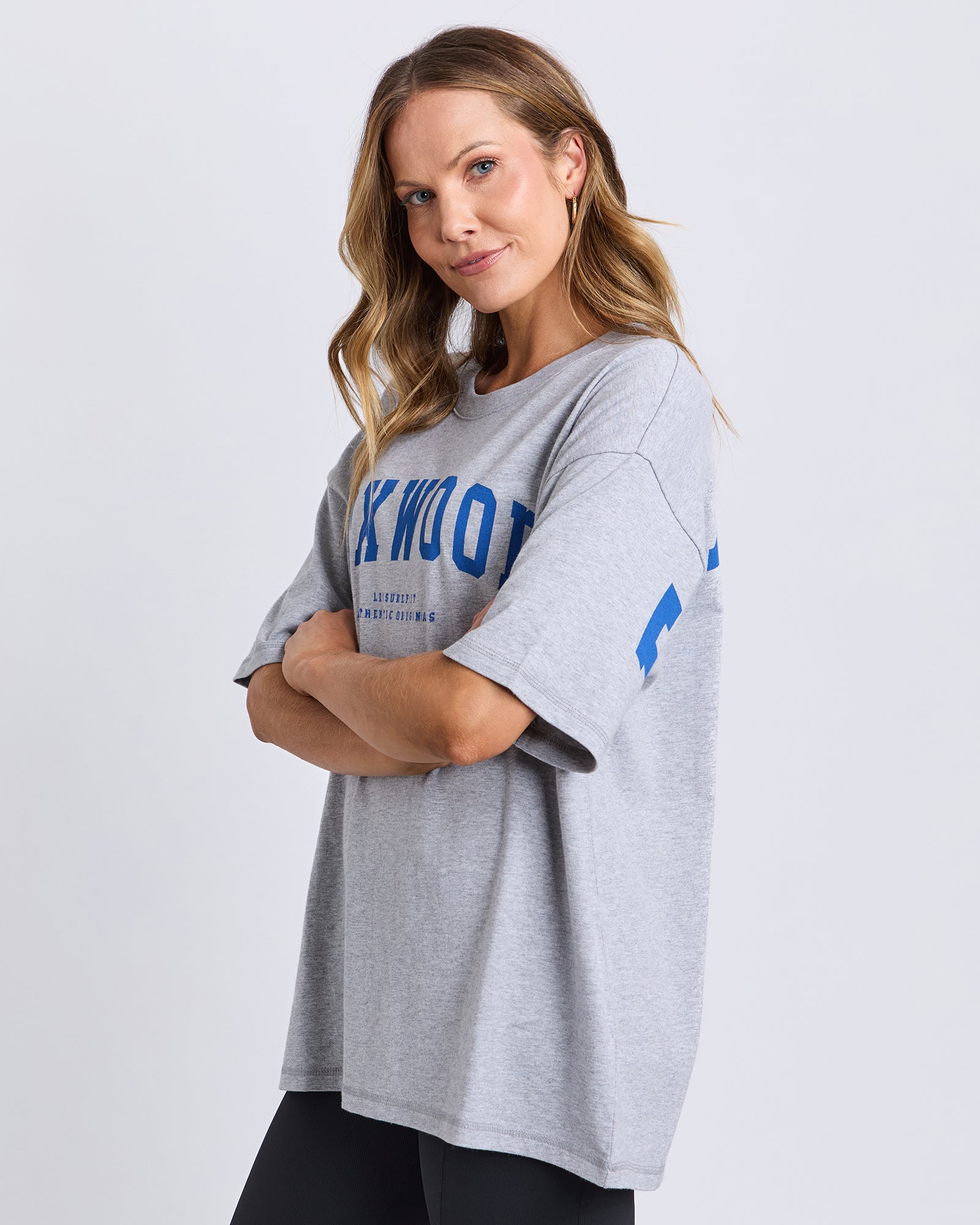 Image of Woman wearing a Foxwood grey oversized t-shirt with blue text on a white background
