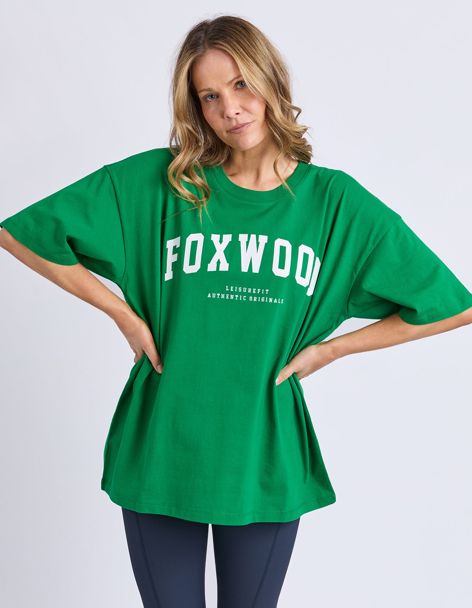 Collection of Woman wearing a green Foxwood t-shirt with 'FOXWOOD' printed on it against a white background in a gallery layout