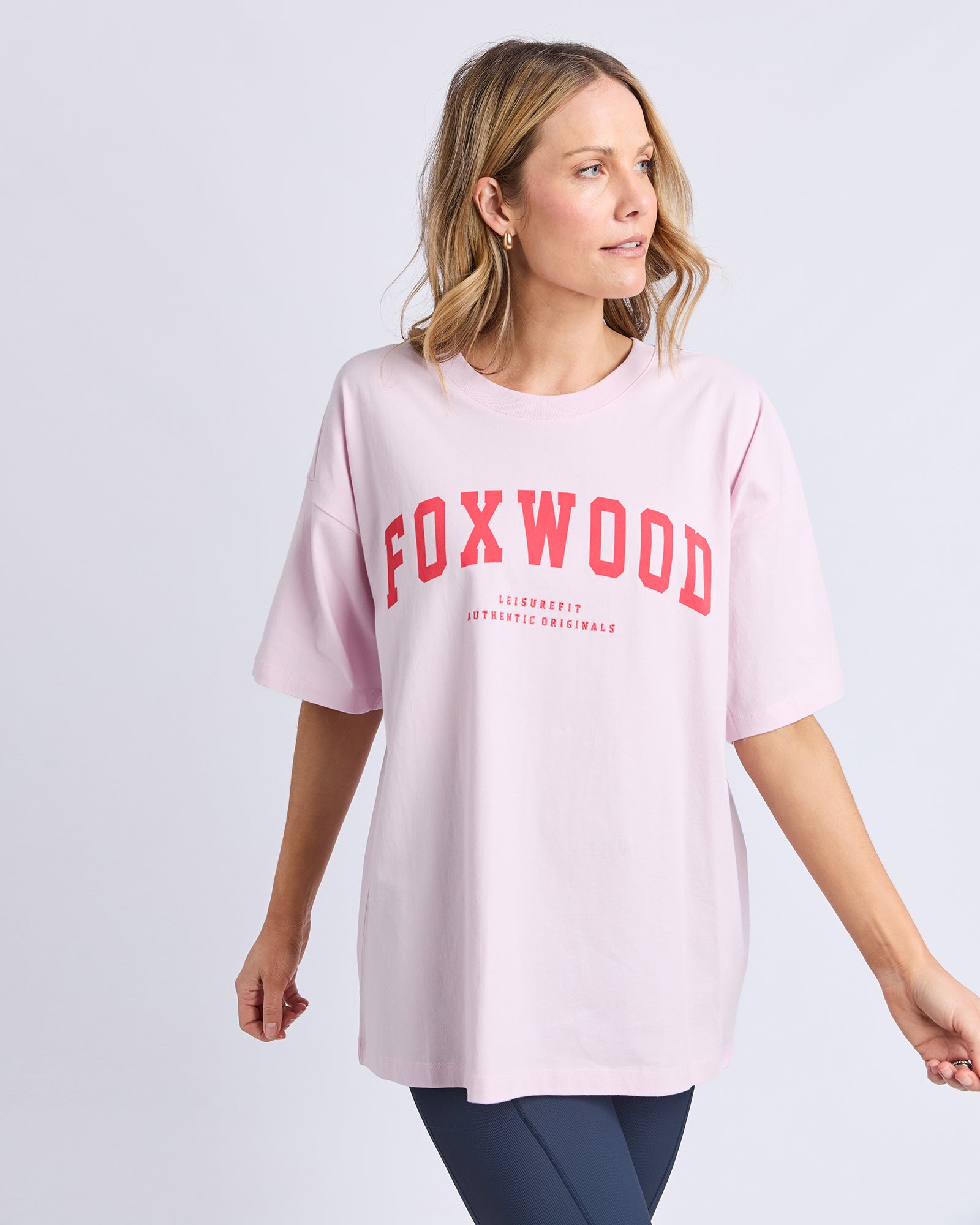 Collection of Woman wearing a pink t-shirt with 'FOXWOOD' printed on it against a light gray background in a gallery layout