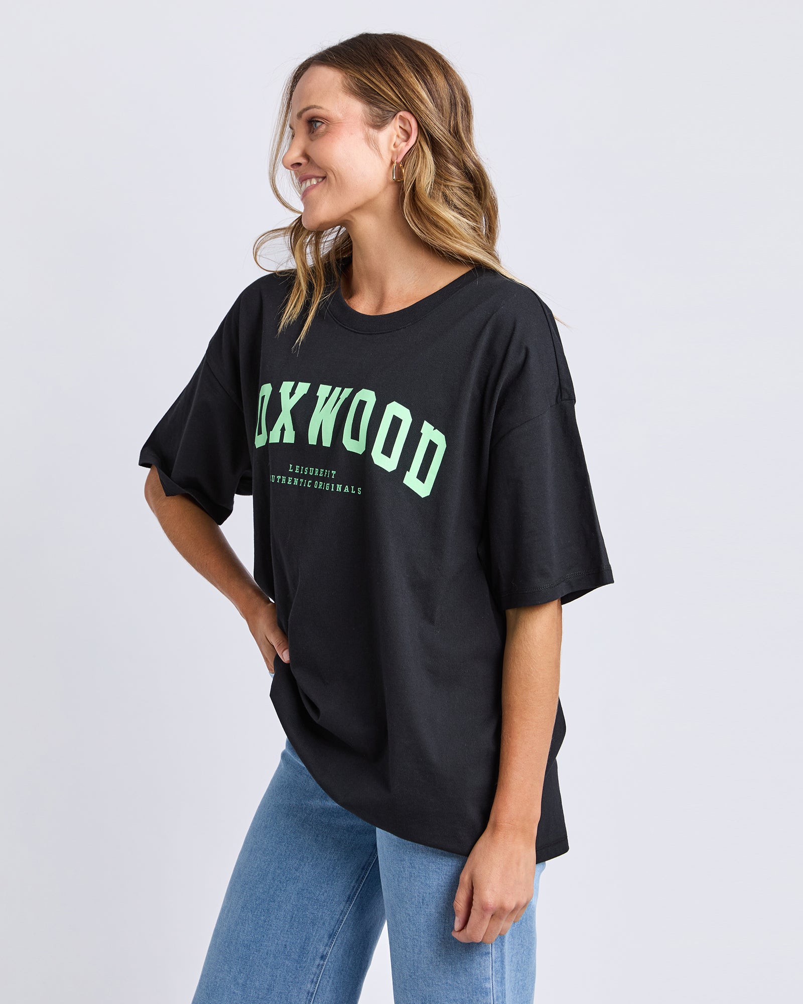 Woman wearing a Foxwood black t-shirt with green text on a white background
