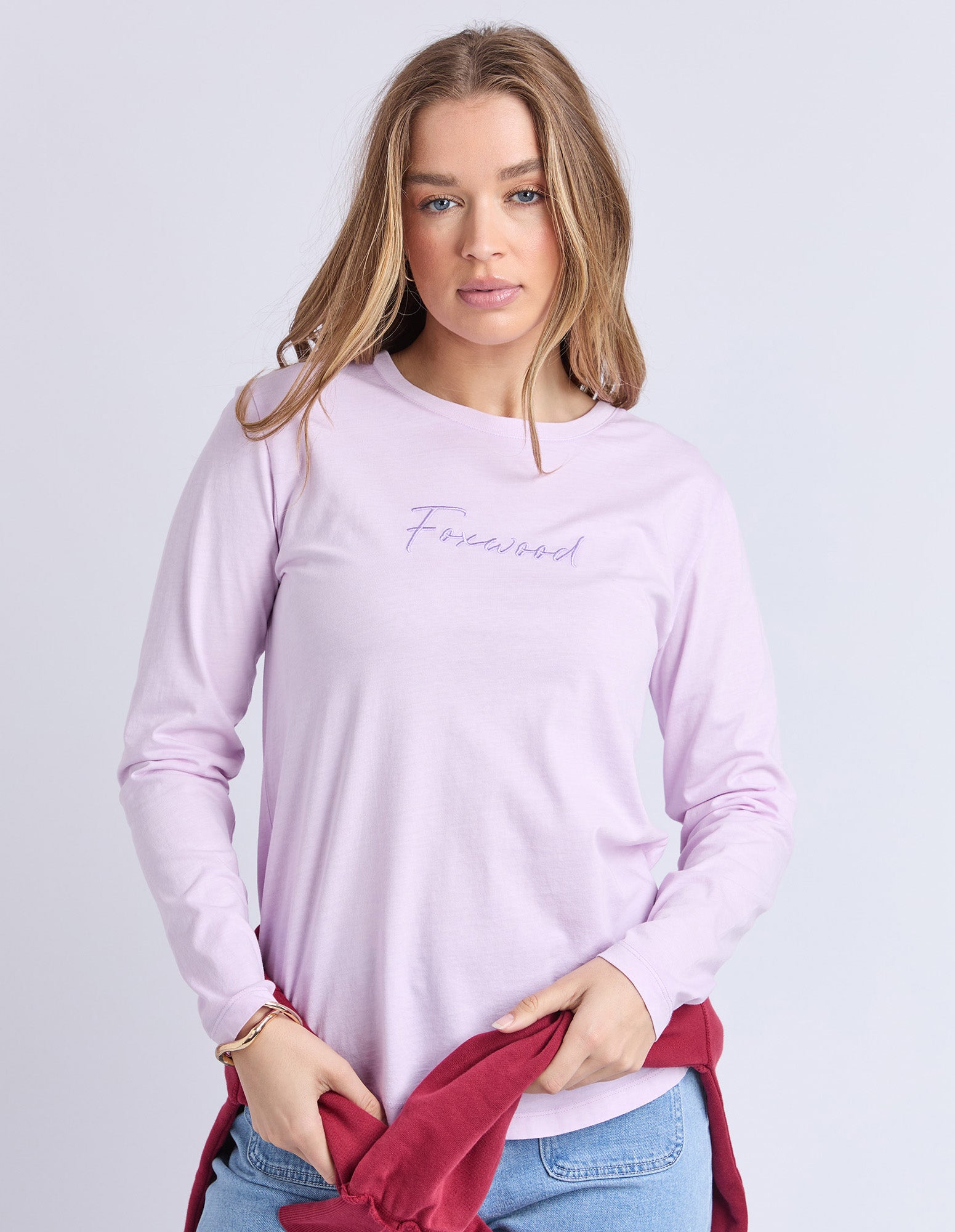 Woman wearing a Foxwood light purple long-sleeve tee with text on a plain background