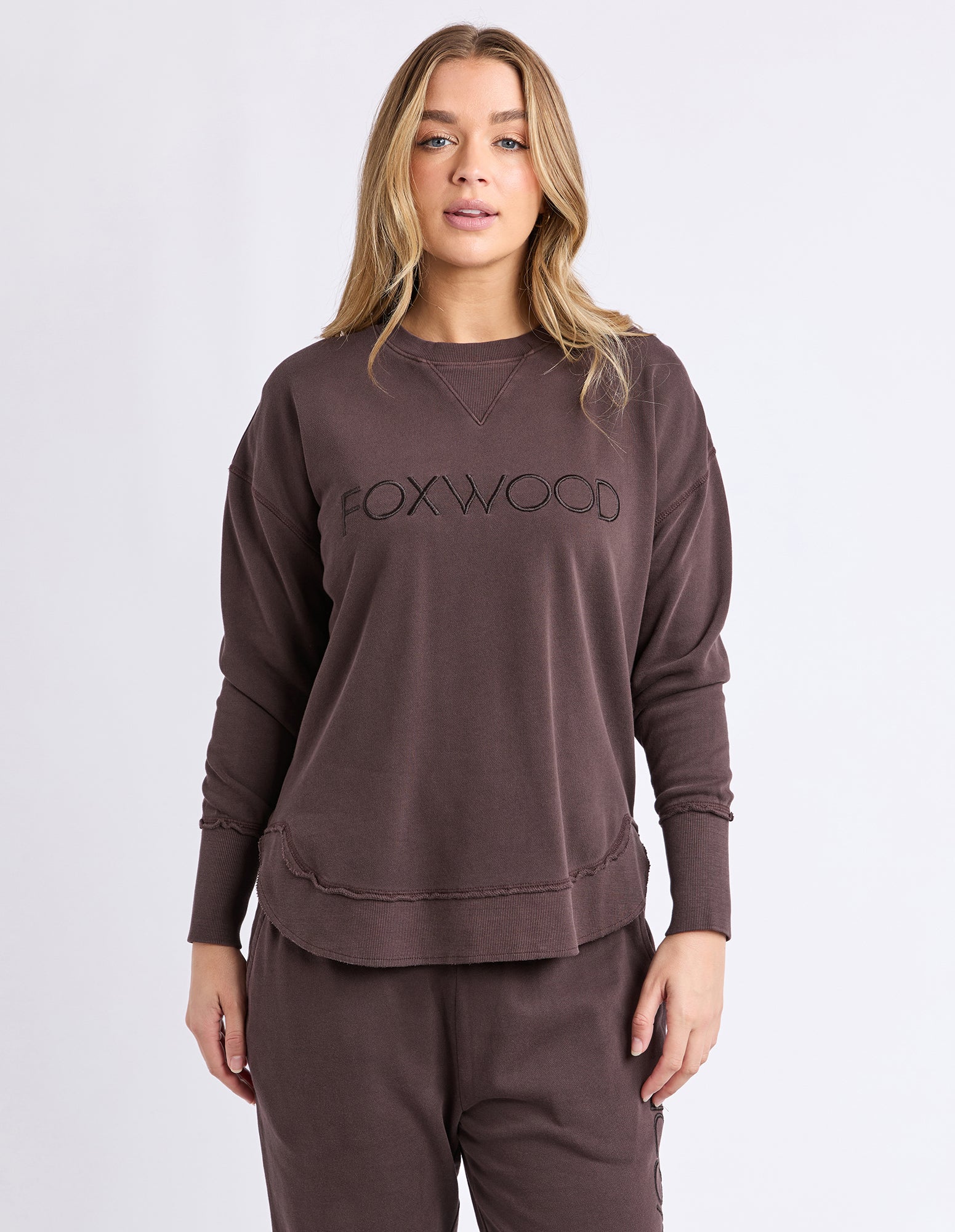 Woman wearing a brown 'FOXWOOD' jumper on a white background