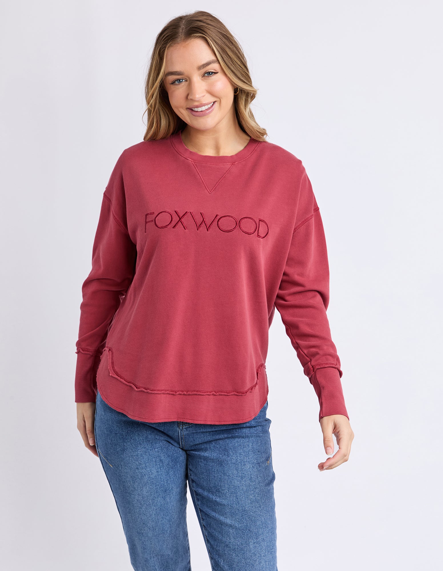 Collection of Woman wearing a red 'FOXWOOD' jumper on a light grae background in a gallery layout