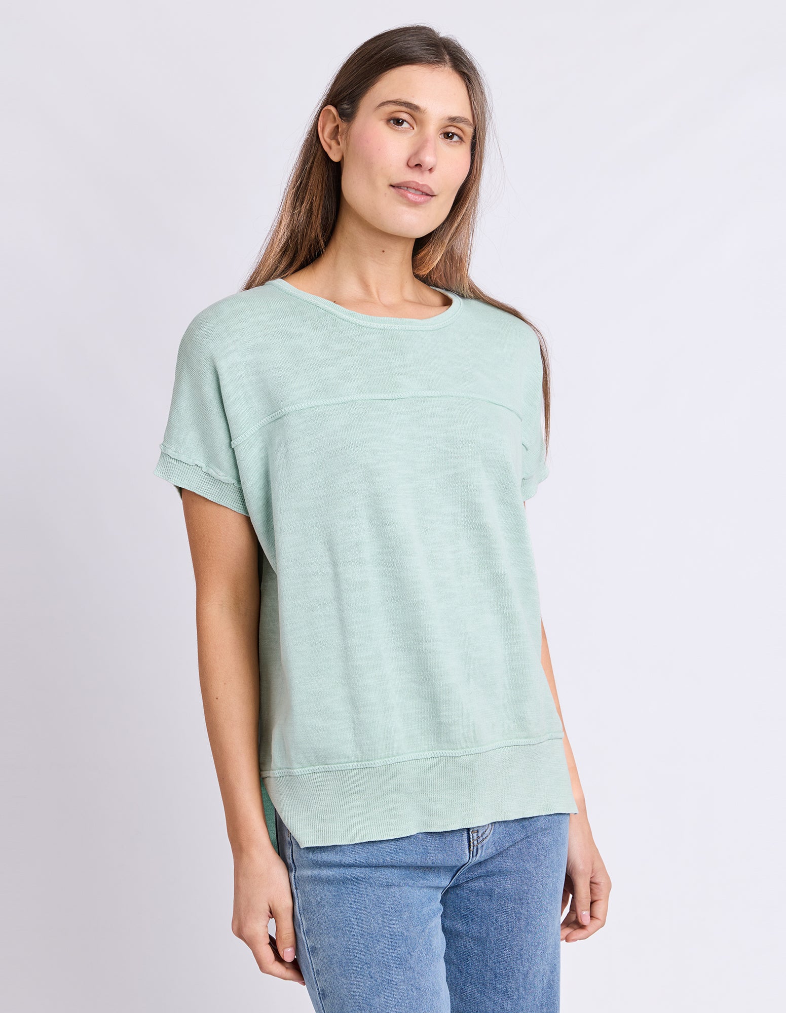Image of A woman wearing a Foxwood light mint green short-sleeve crewneck top and blue jeans, standing against a plain light gray studio background.