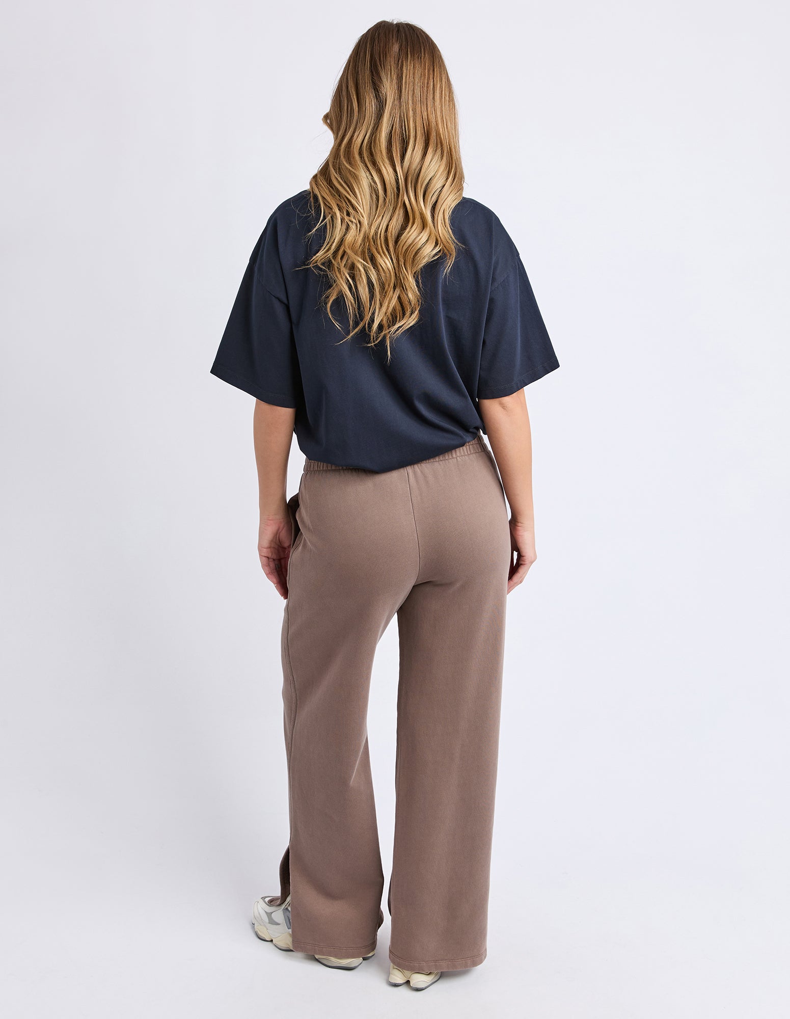 Image of Woman wearing a navy top and Foxwood brown pants on a white background