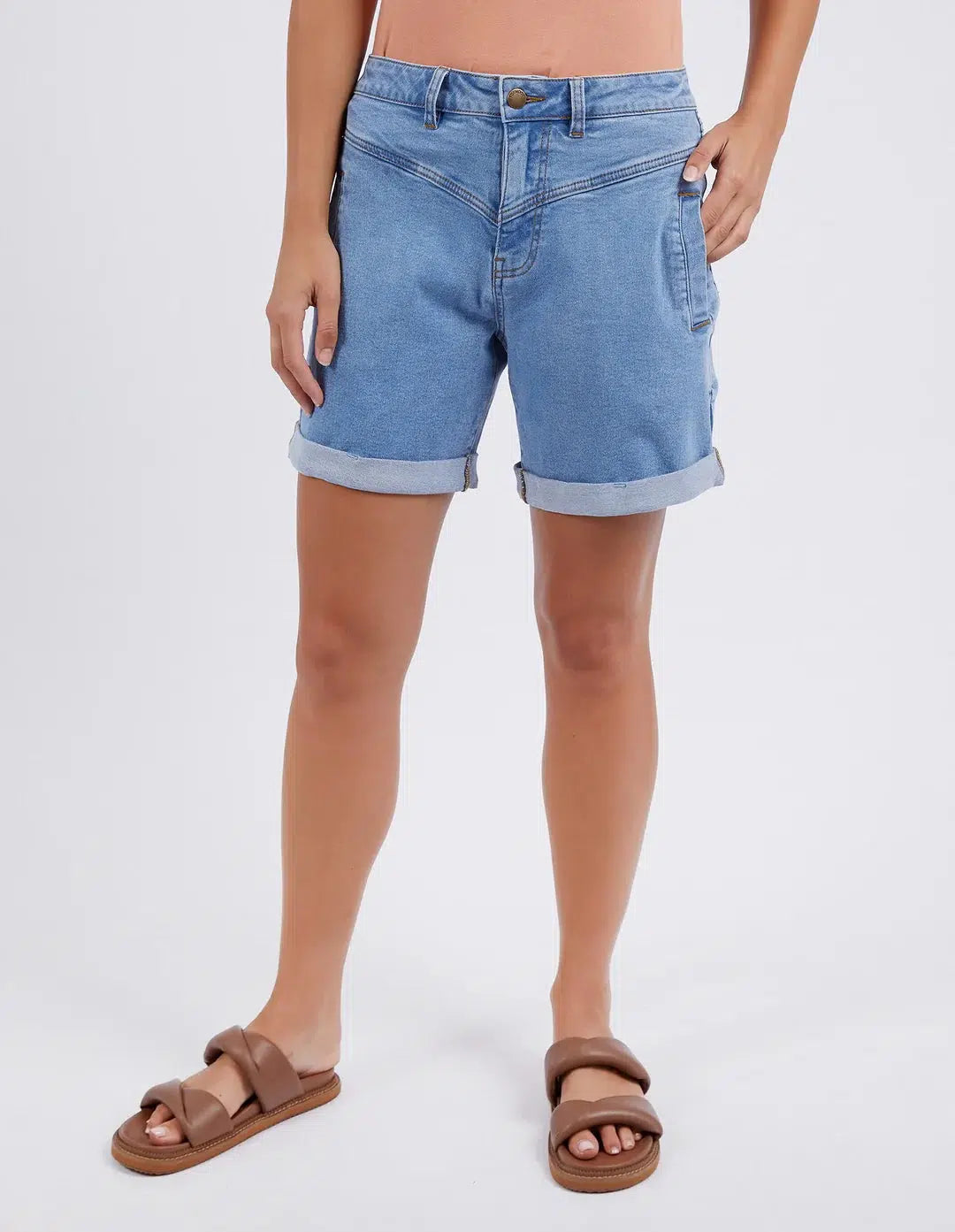 Image of A model wearing Foxwood light blue denim shorts with rolled cuffs and brown double-strap sandals, shown from the waist down against a light gray studio background.