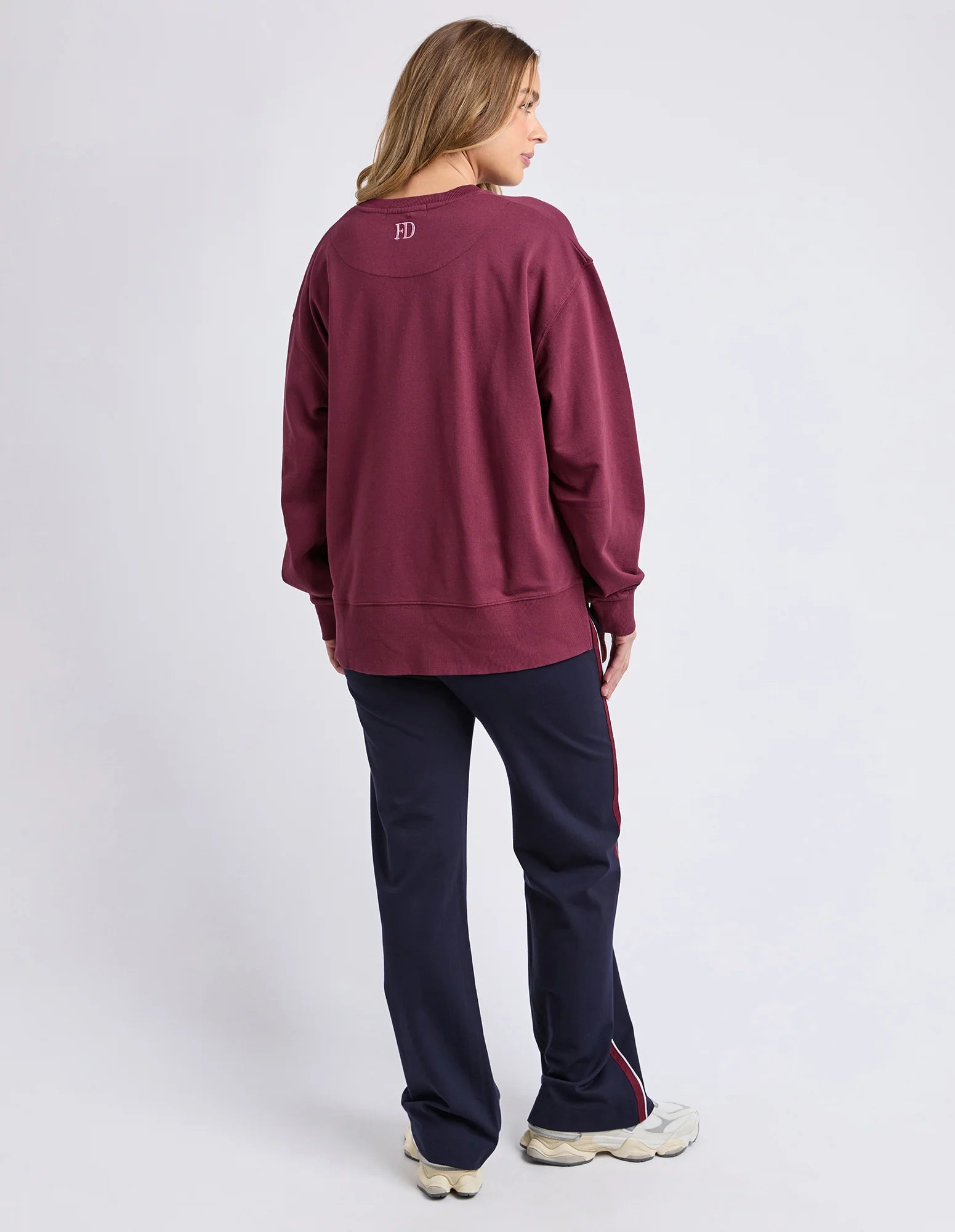 Image of Woman wearing a Foxwood maroon sweatshirt and navy pants on a white background