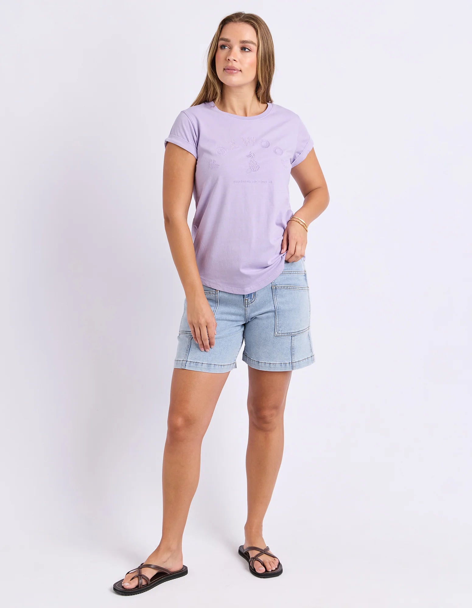 Image of A woman modeling a Foxwood light purple short-sleeve t-shirt and light blue denim shorts against a plain white studio background.