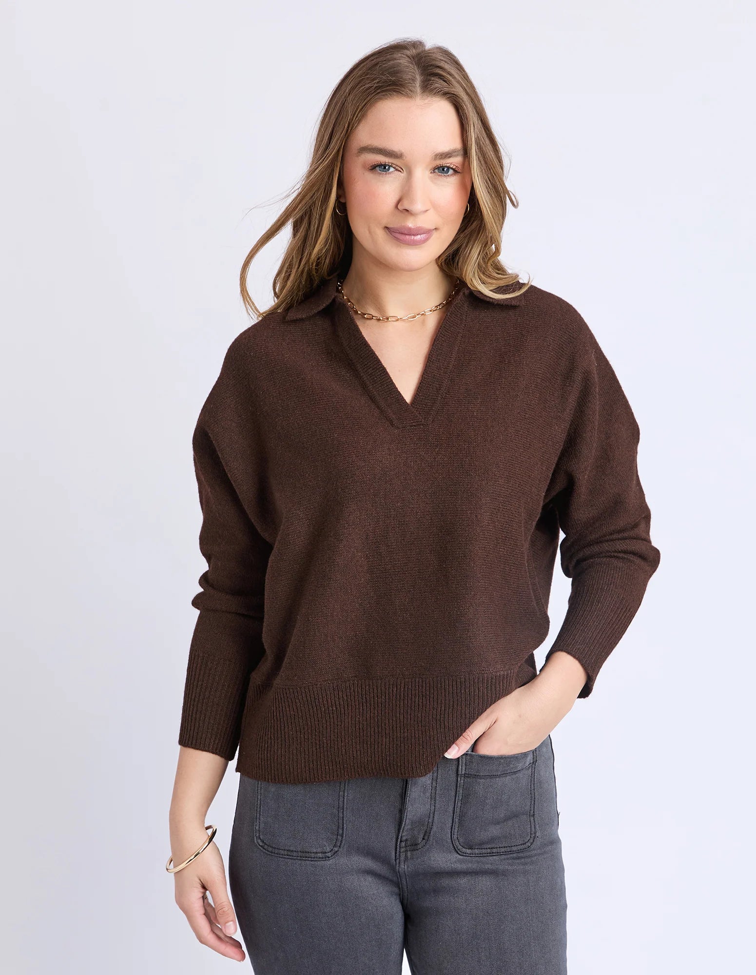 Image of Woman wearing a Foxwood brown sweater and gray jeans against a white background
