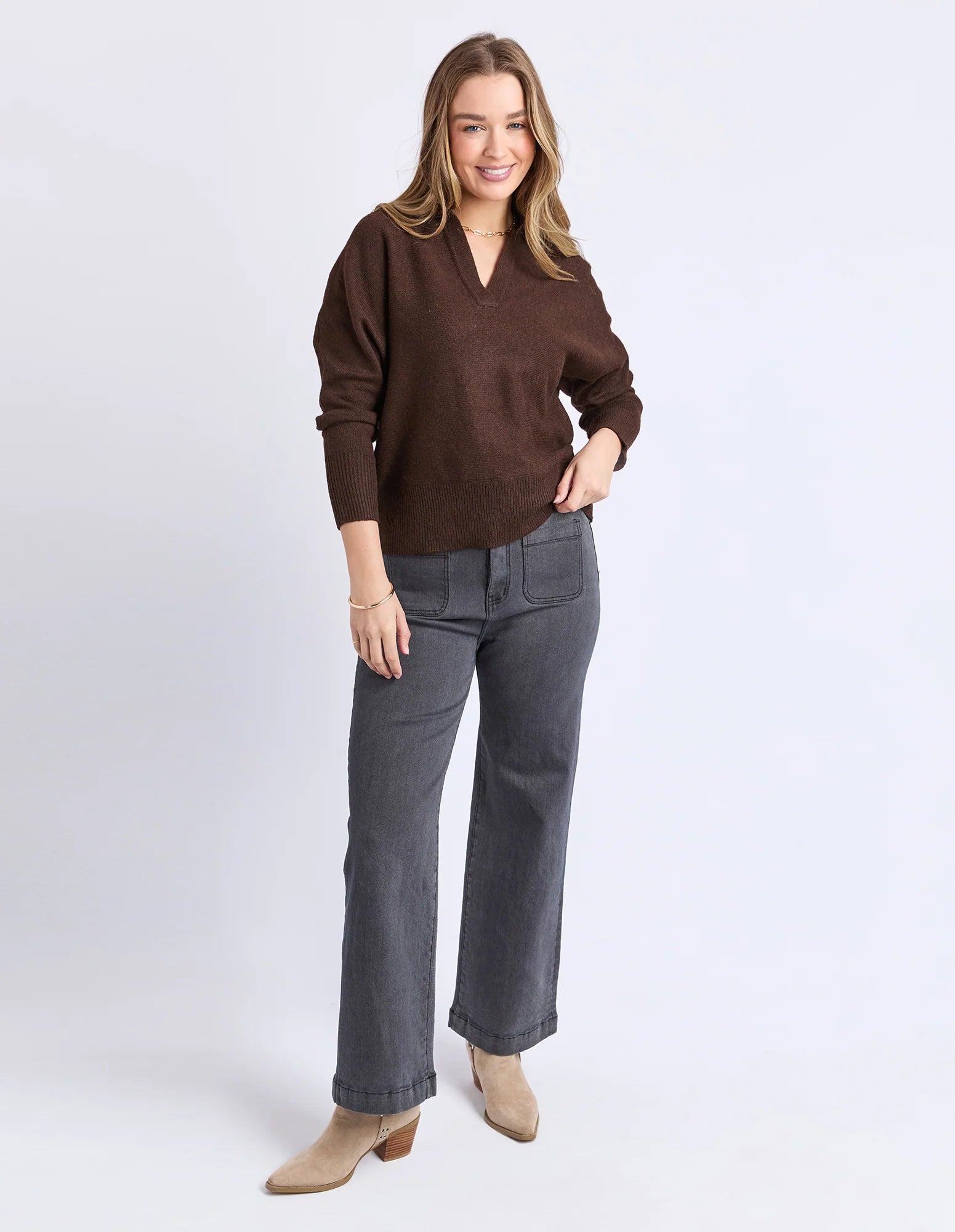 Image of Woman wearing a Foxwood brown sweater and gray pants on a white background