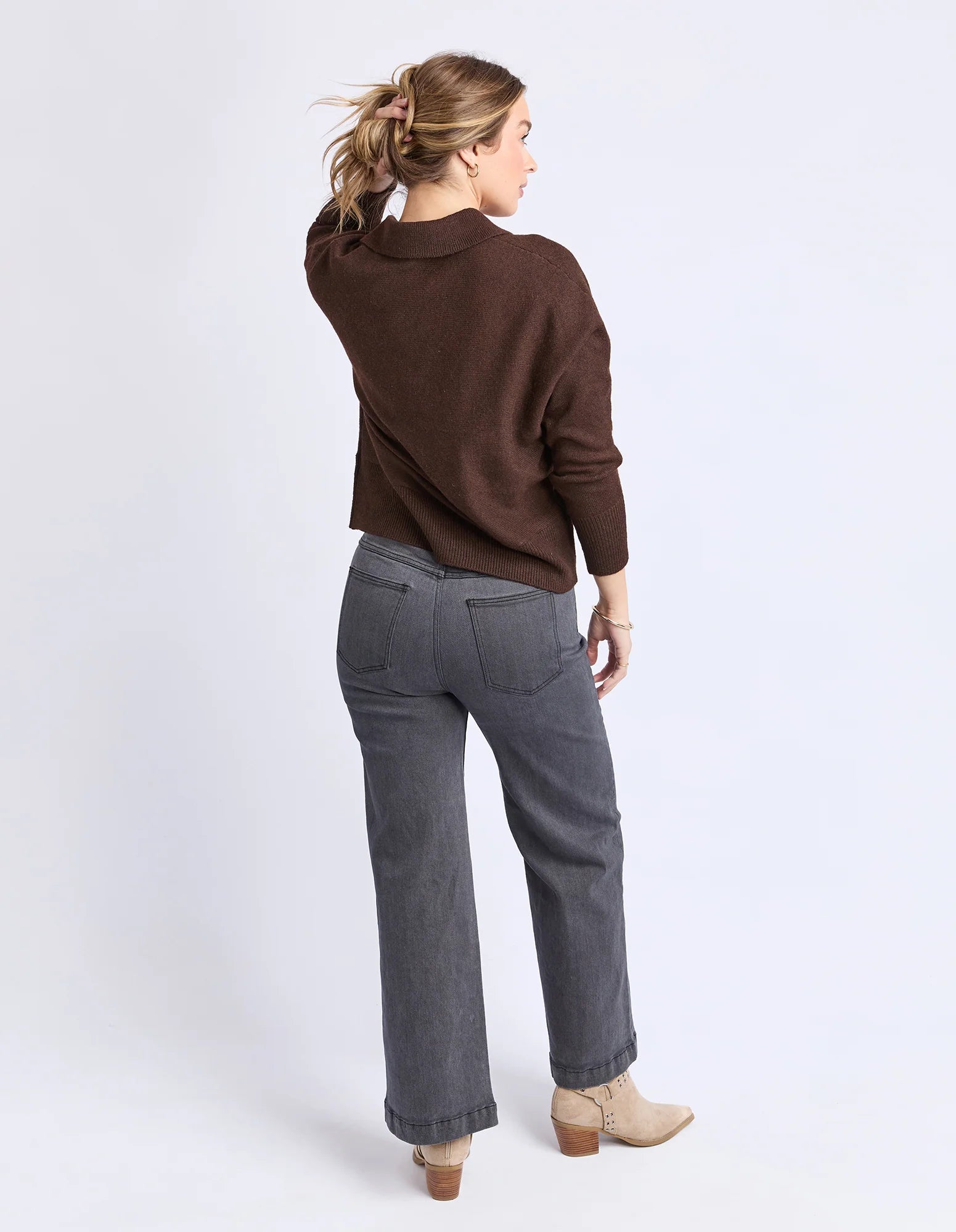 Image of Woman wearing a Foxwood brown sweater and gray pants on a white background