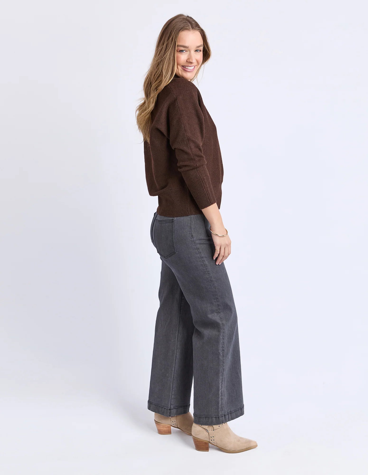 Image of Woman wearing a Foxwood brown sweater and gray pants on a white background
