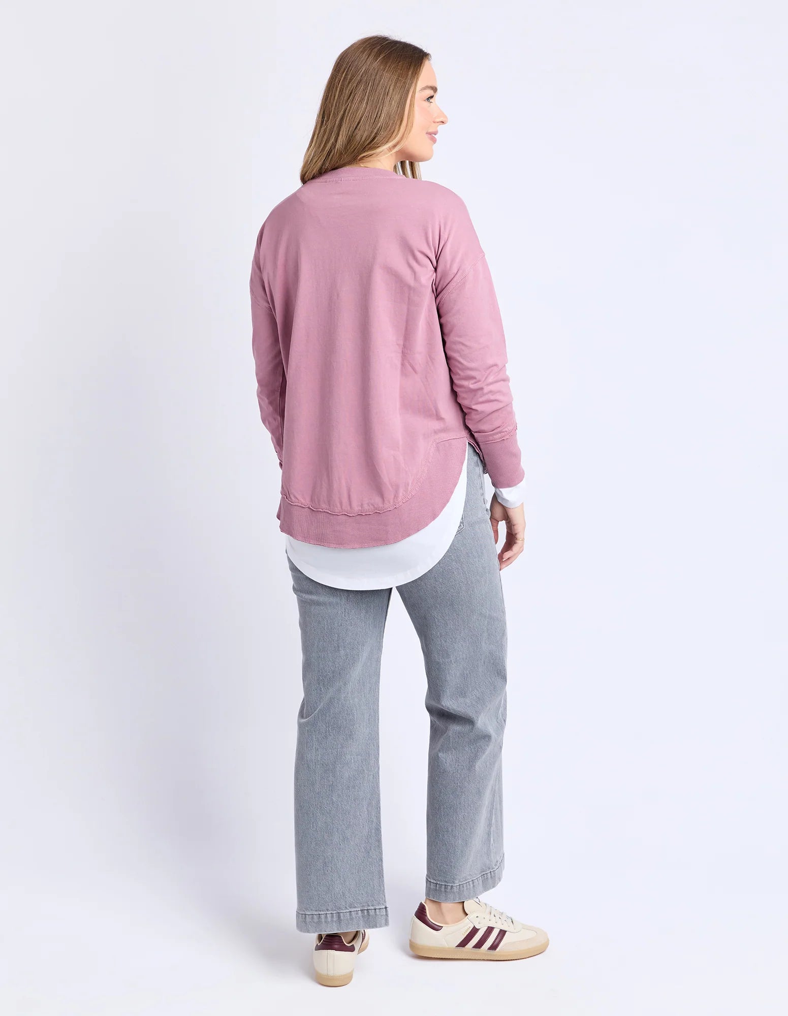 Image of Woman wearing a Foxwood pink sweatshirt and gray pants on a white background
