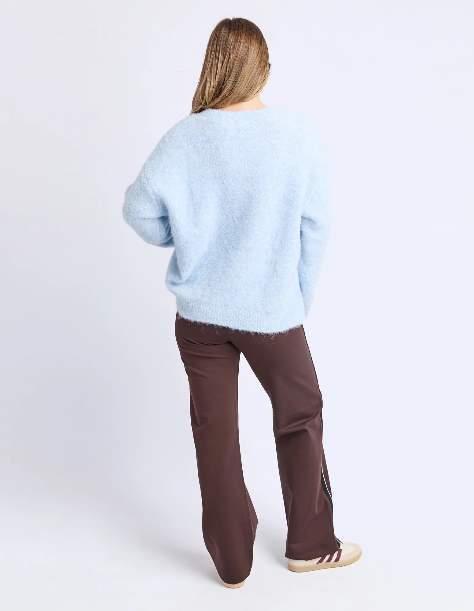 Image of Woman wearing a Foxwood light blue sweater and brown pants on a white background