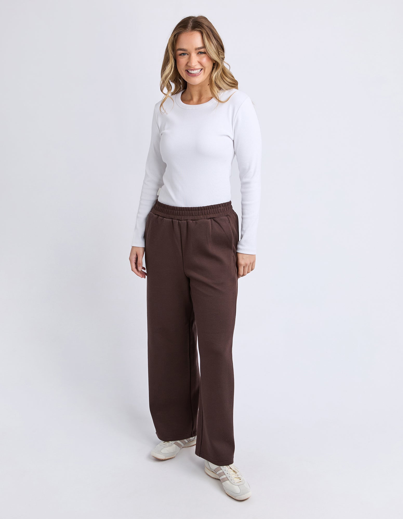 Woman wearing Foxwood brown wide-leg pants and a white top on a white background