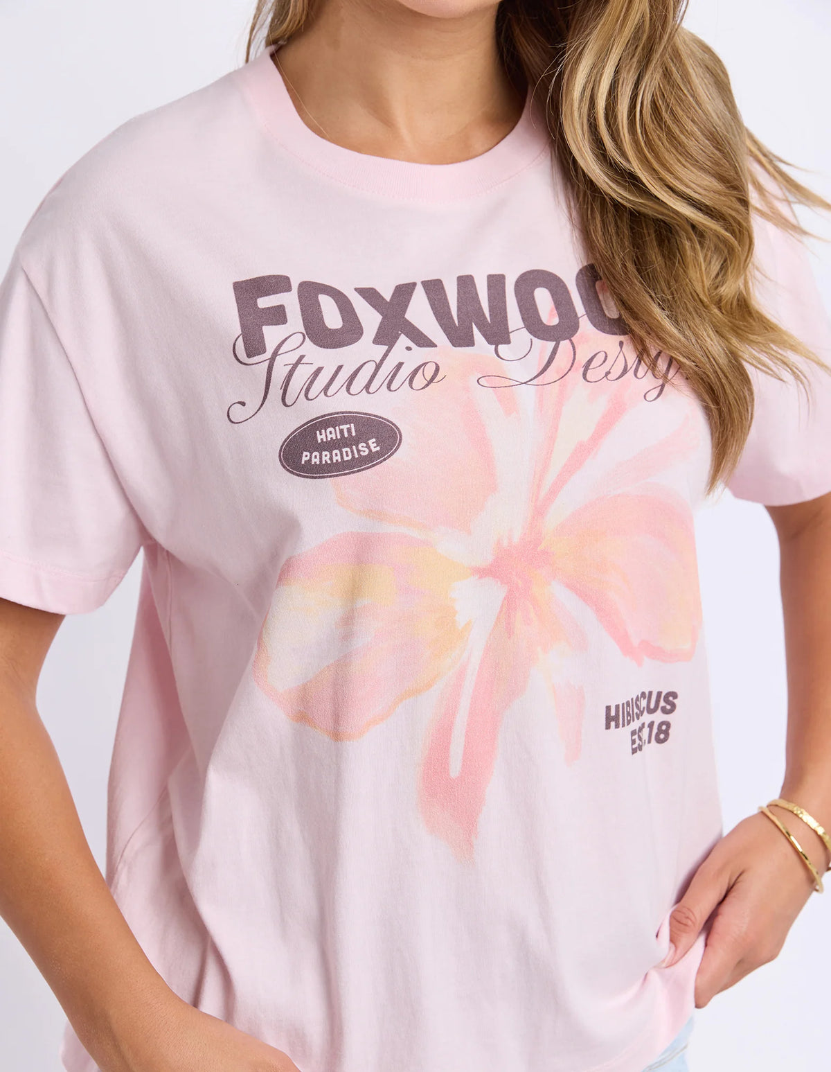 Woman wearing Foxwood printed hisbiscus shirt paired with denim jeans on a plain background 