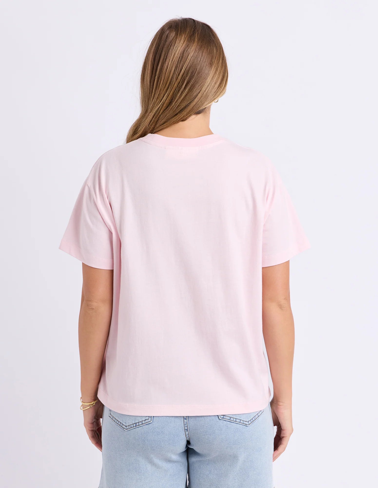 Image of Woman wearing Foxwood printed hisbiscus shirt paired with denim jeans on a plain background 