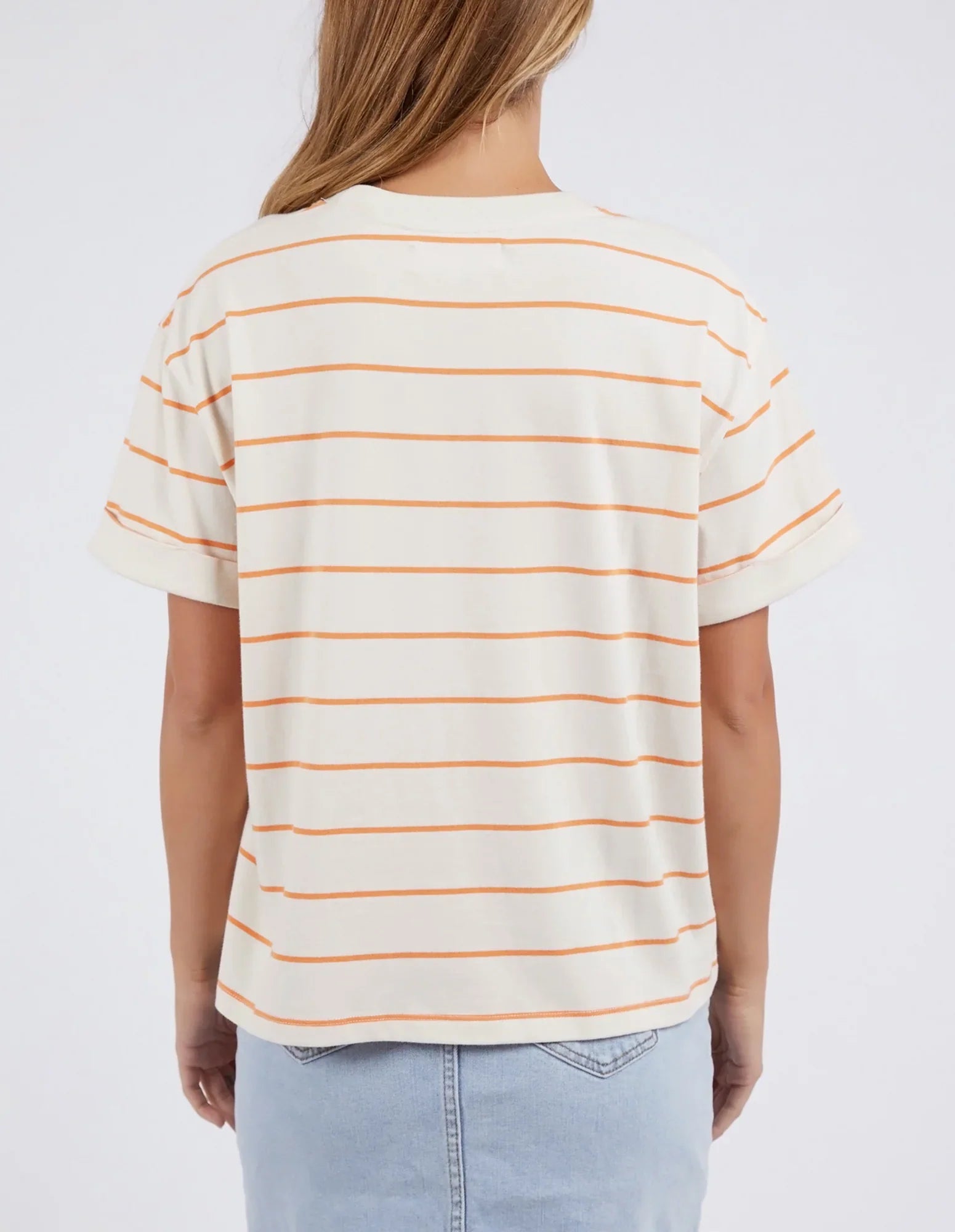 Image of A woman viewed from the back wearing a Foxwood cream-colored short-sleeve t-shirt with thin orange horizontal stripes, paired with light blue jeans, against a plain white background.