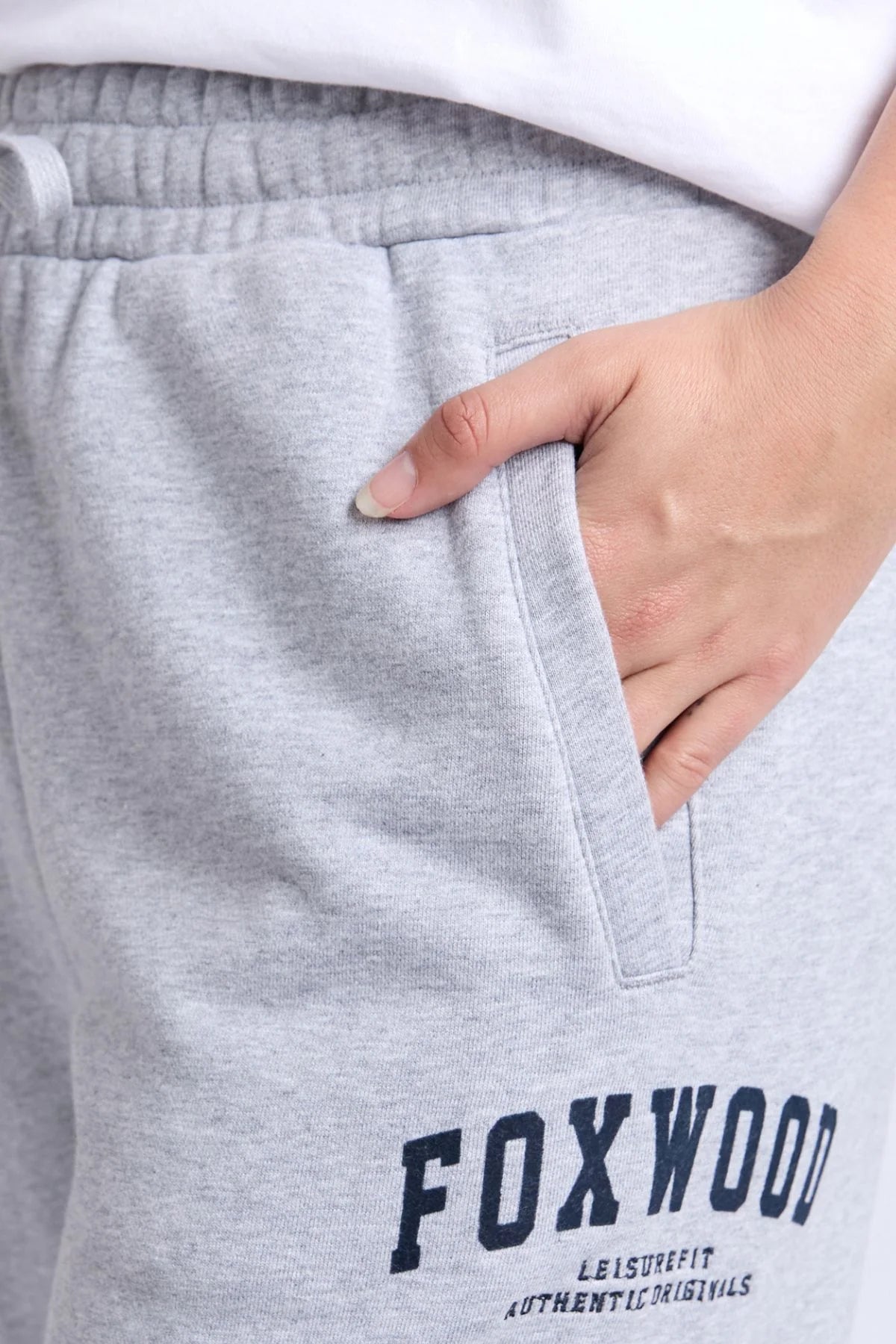 Image of Woman wearing grey Foxwood trackpants with a white top on a plain background 