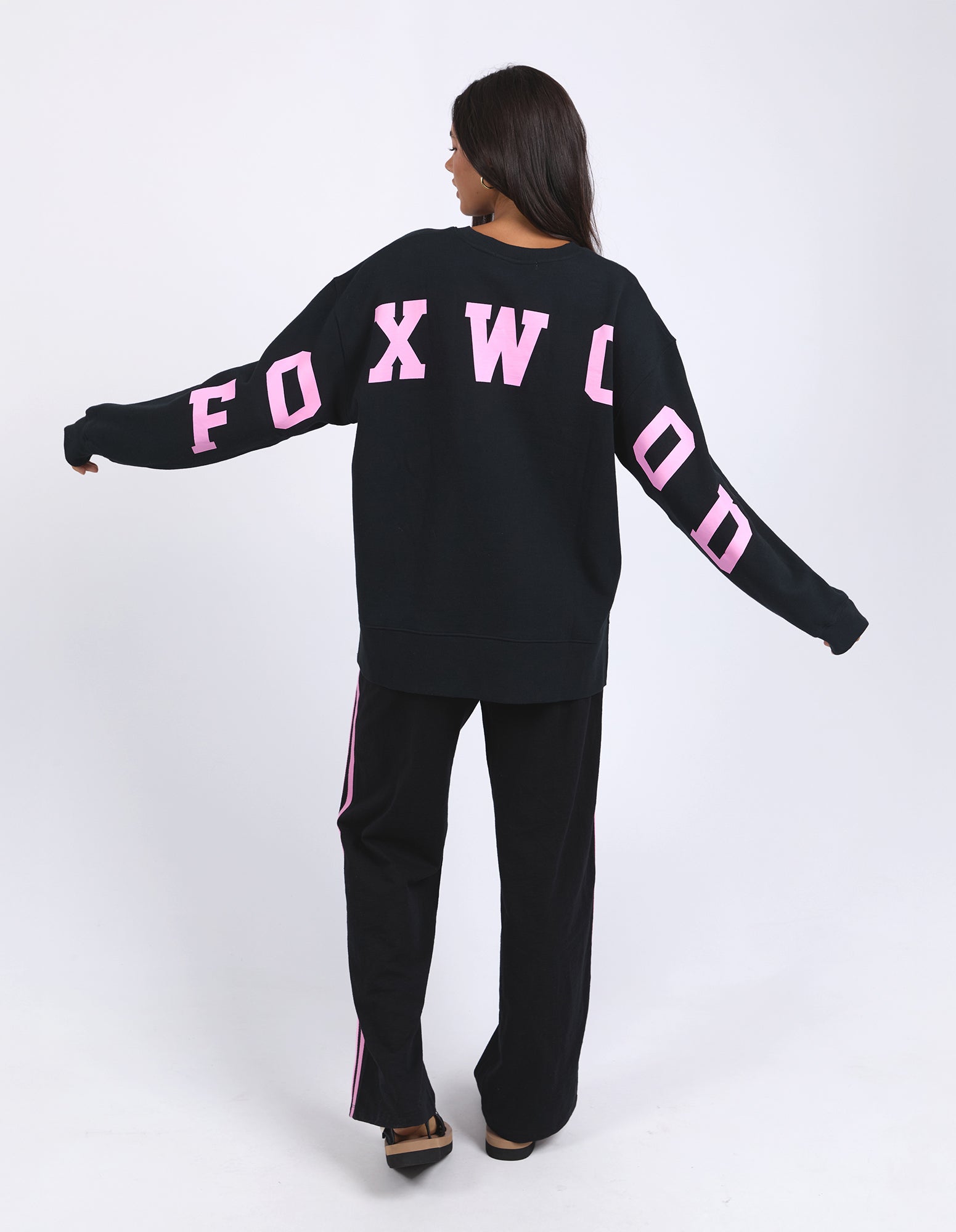 Image of Woman wearing a black outfit with pink text on a white background