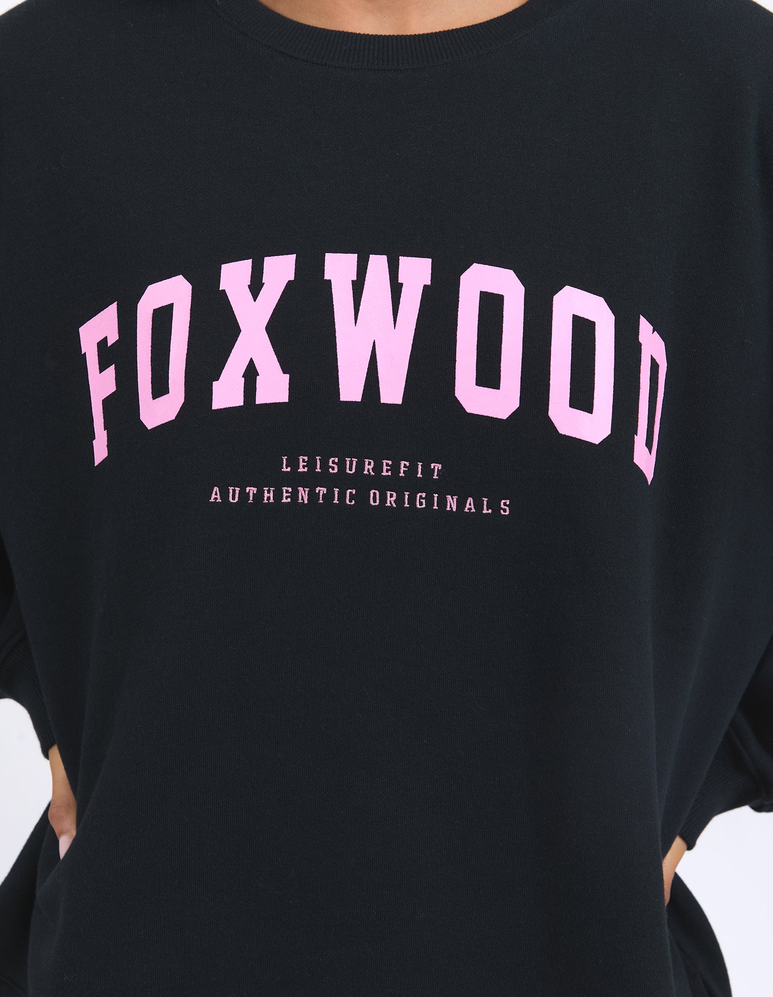 Image of Black shirt with pink 'FOXWOOD' text and 'AUTHENTIC ORIGINALS' below on a plain background.