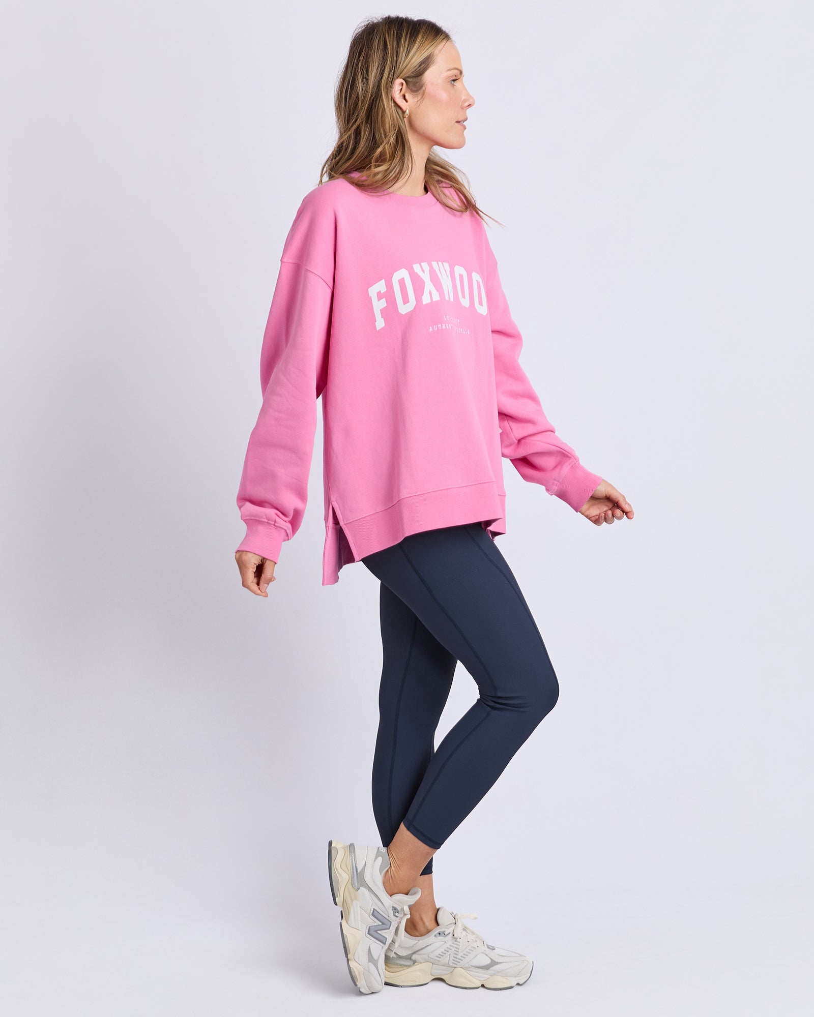 Image of Woman wearing a Foxwood pink sweatshirt with 'FOXWOOD' text on a light gray background