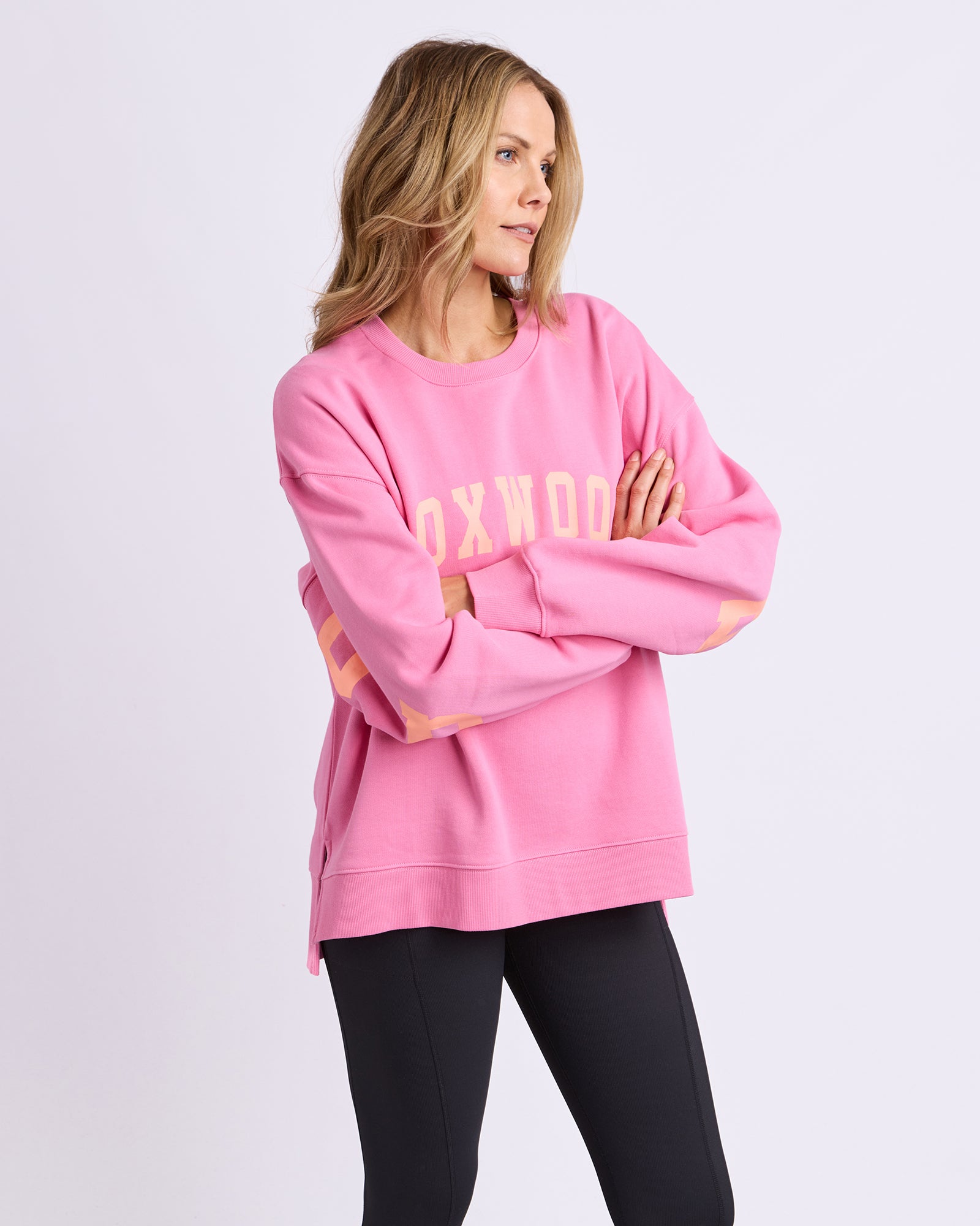 Image of Woman wearing a pink sweatshirt with 'OXFORD' printed on it against a white background