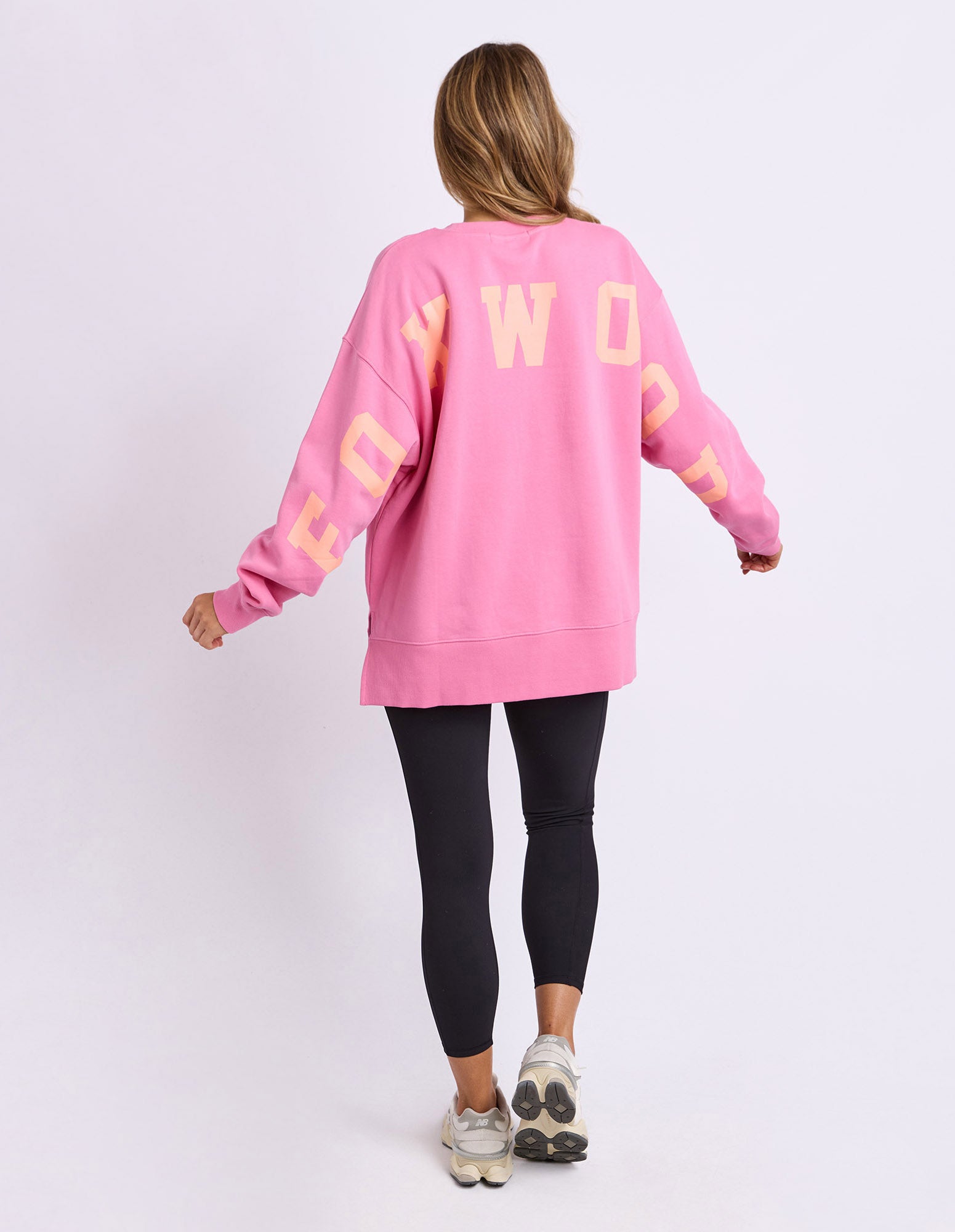 Woman wearing pink Foxwood interval crew with black leggings on a white background