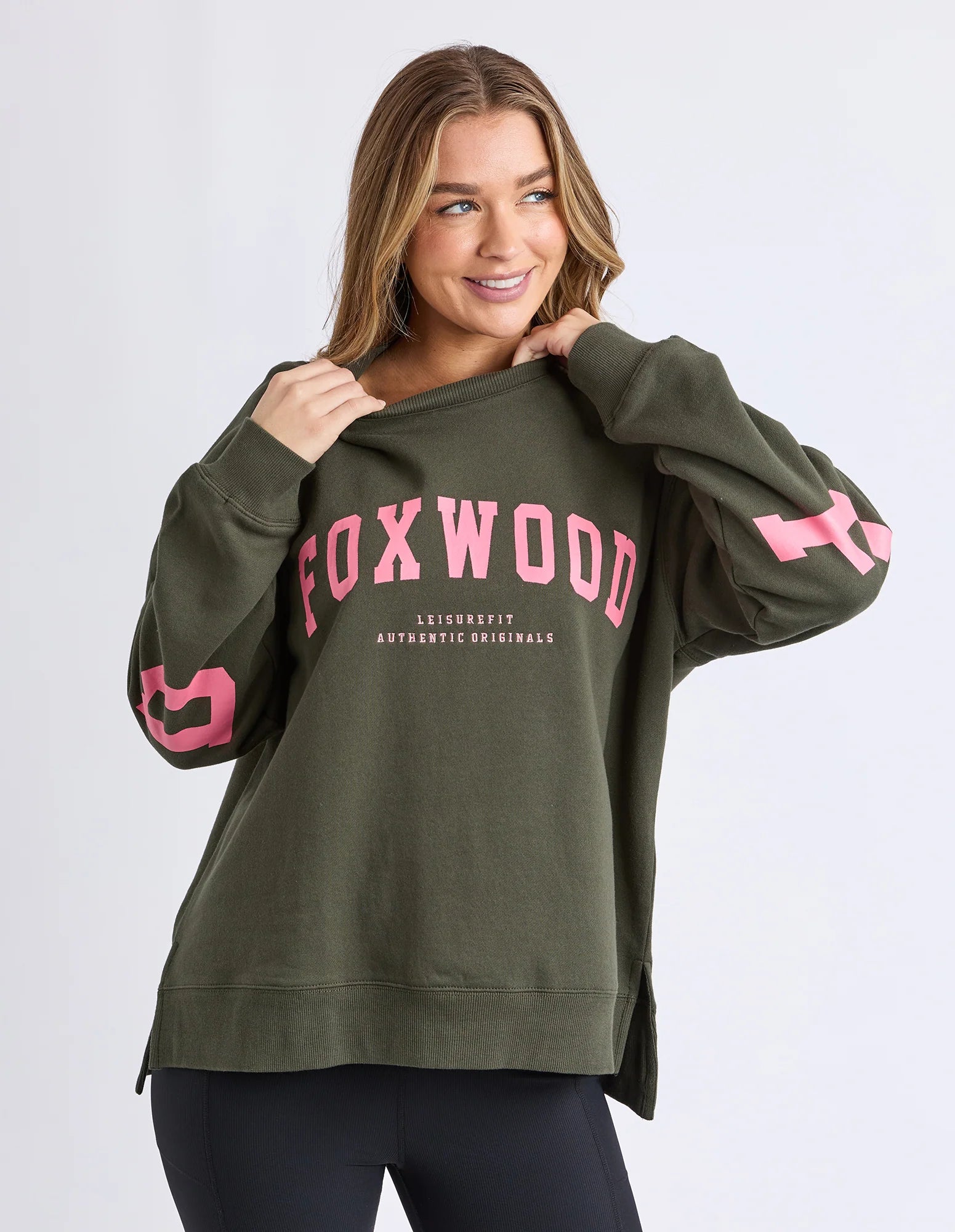 Image of Woman wearing a Foxwood green sweatshirt with pink text on a white background