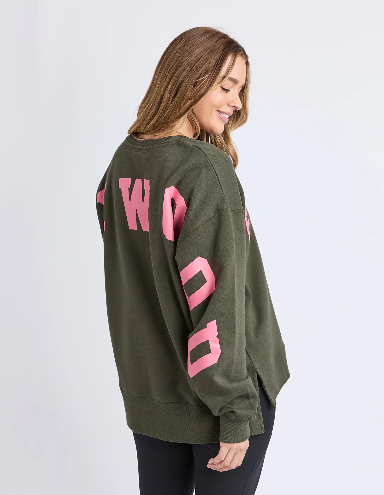 Woman wearing a Foxwood green sweatshirt with pink text on a white background
