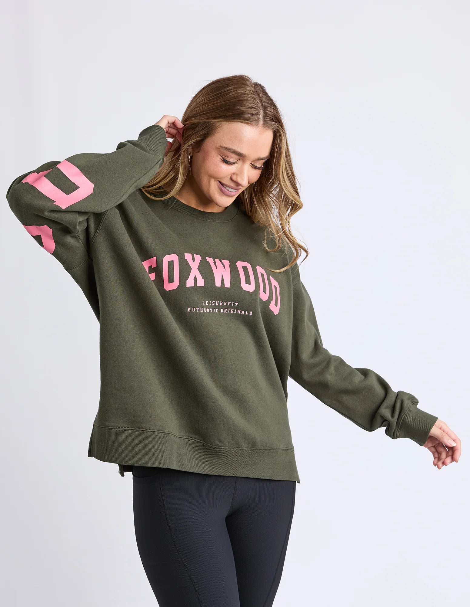 Woman wearing a Foxwood green sweatshirt with pink text on a light gray background
