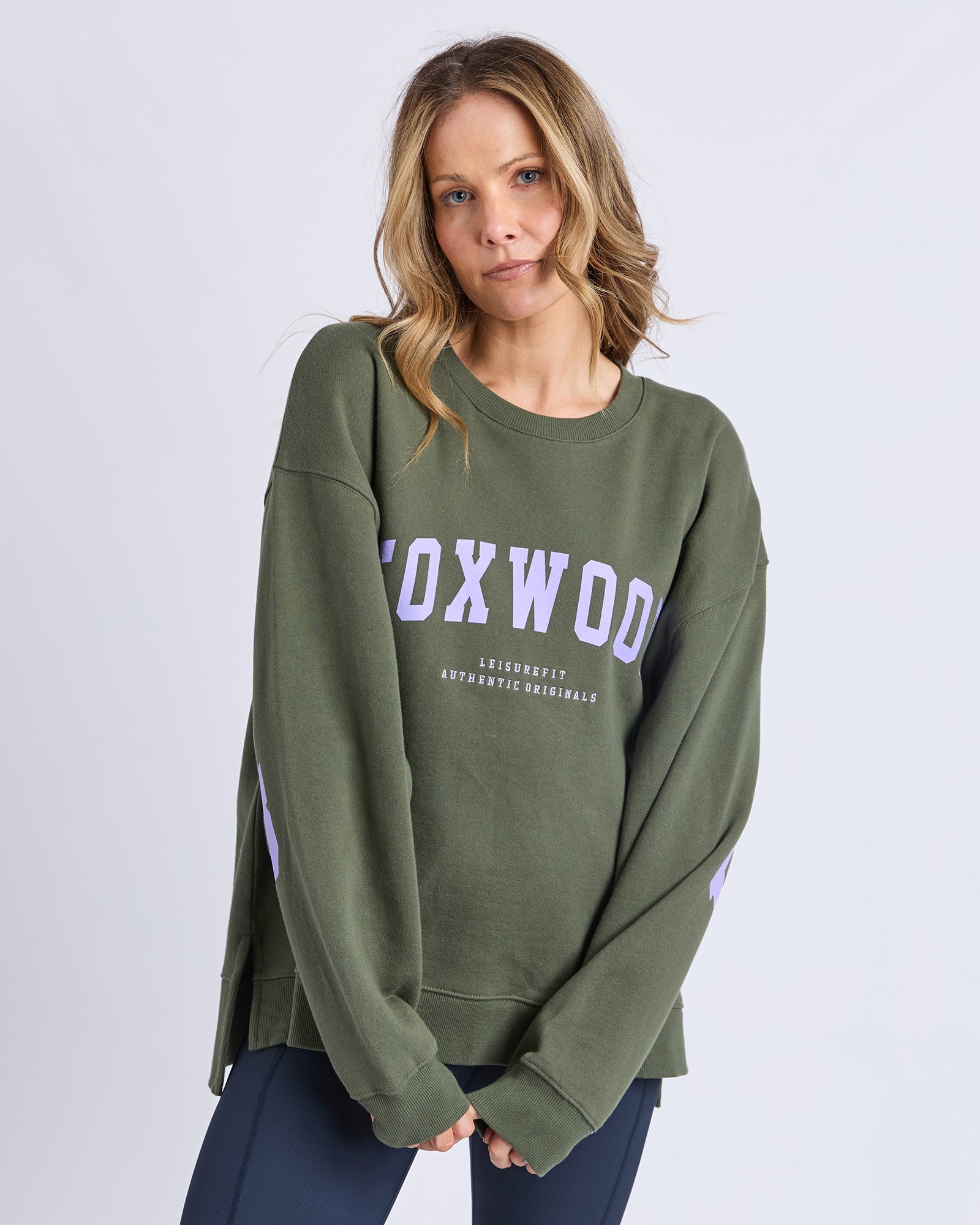 Image of Woman wearing a green sweatshirt with 'Foxwood' printed on it against a white background