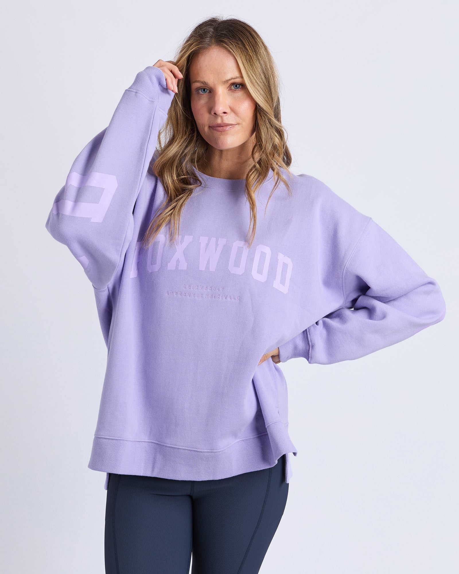 Image of Woman wearing a light purple/lavender jumper with 'FOXWOOD' branding on a white background