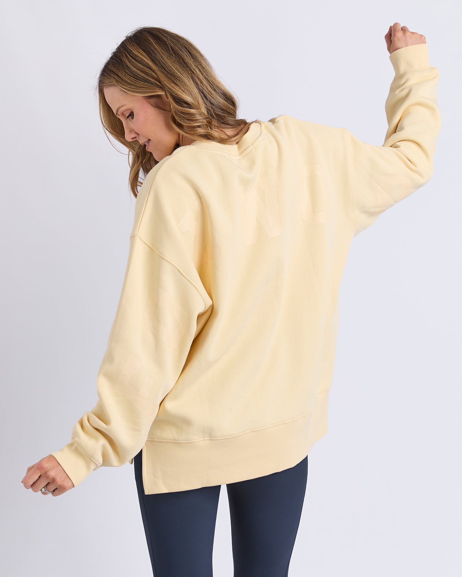 Image of Woman wearing a light yellow/lemon jumper with matching print on a plain background