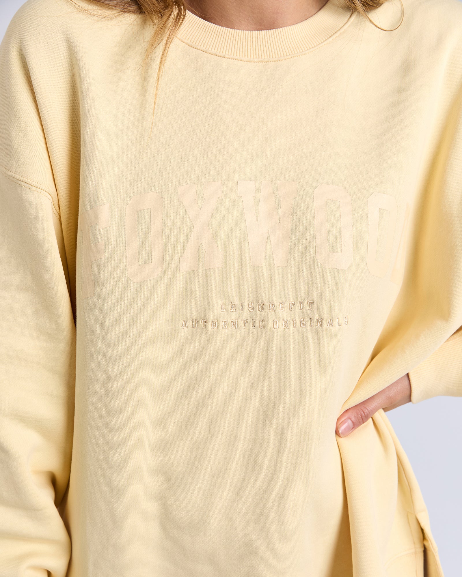 Woman wearing a Yellow/lemon jumper with text on a plain background