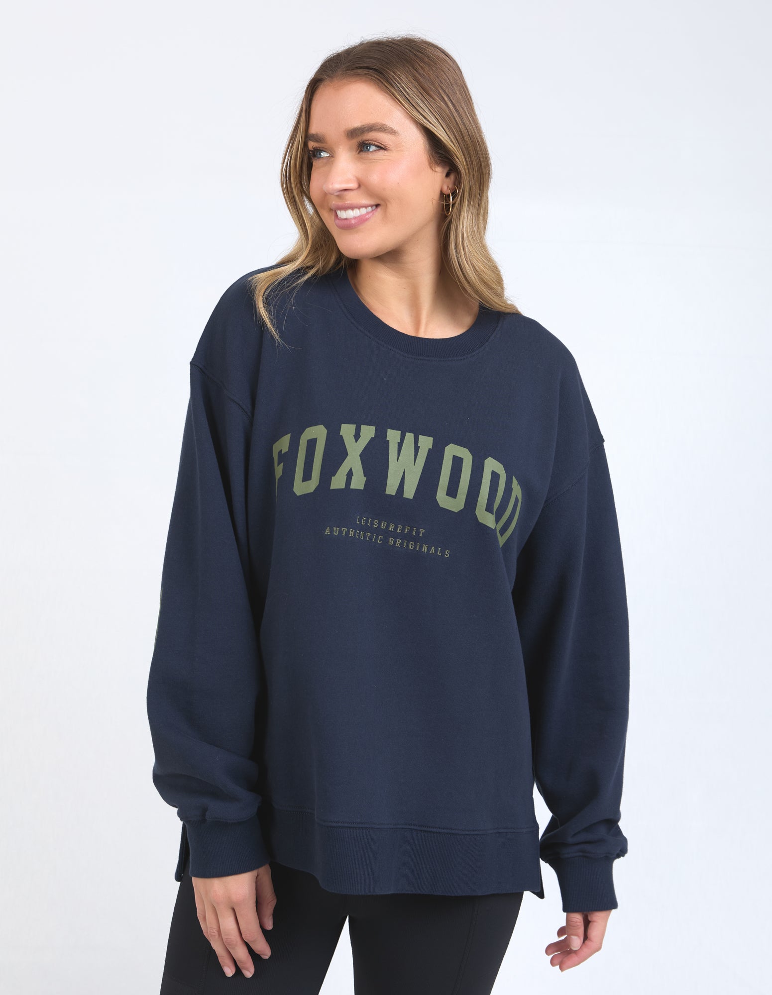 Image of Woman wearing a navy sweatshirt with 'FOXWOOD' printed on it against a white background