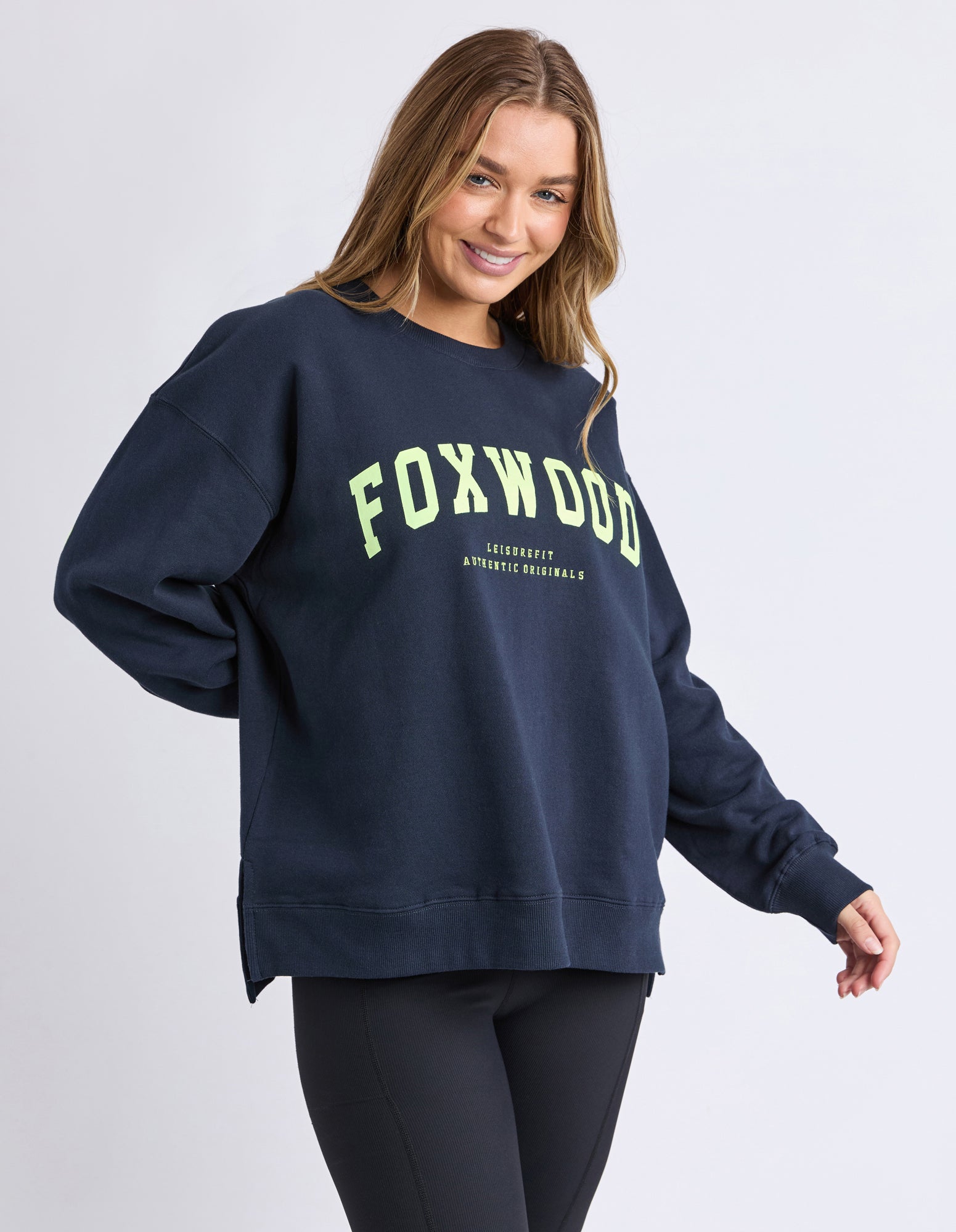 Woman wearing a navy sweatshirt with 'FOXWOOD' printed in yellow on a white background