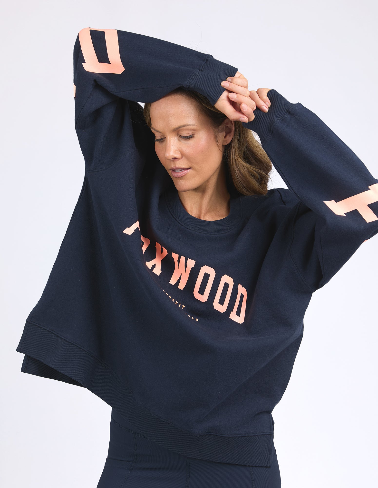 Woman wearing a Foxwood navy blue sweatshirt with 'FOXWOOD' branding on a white background