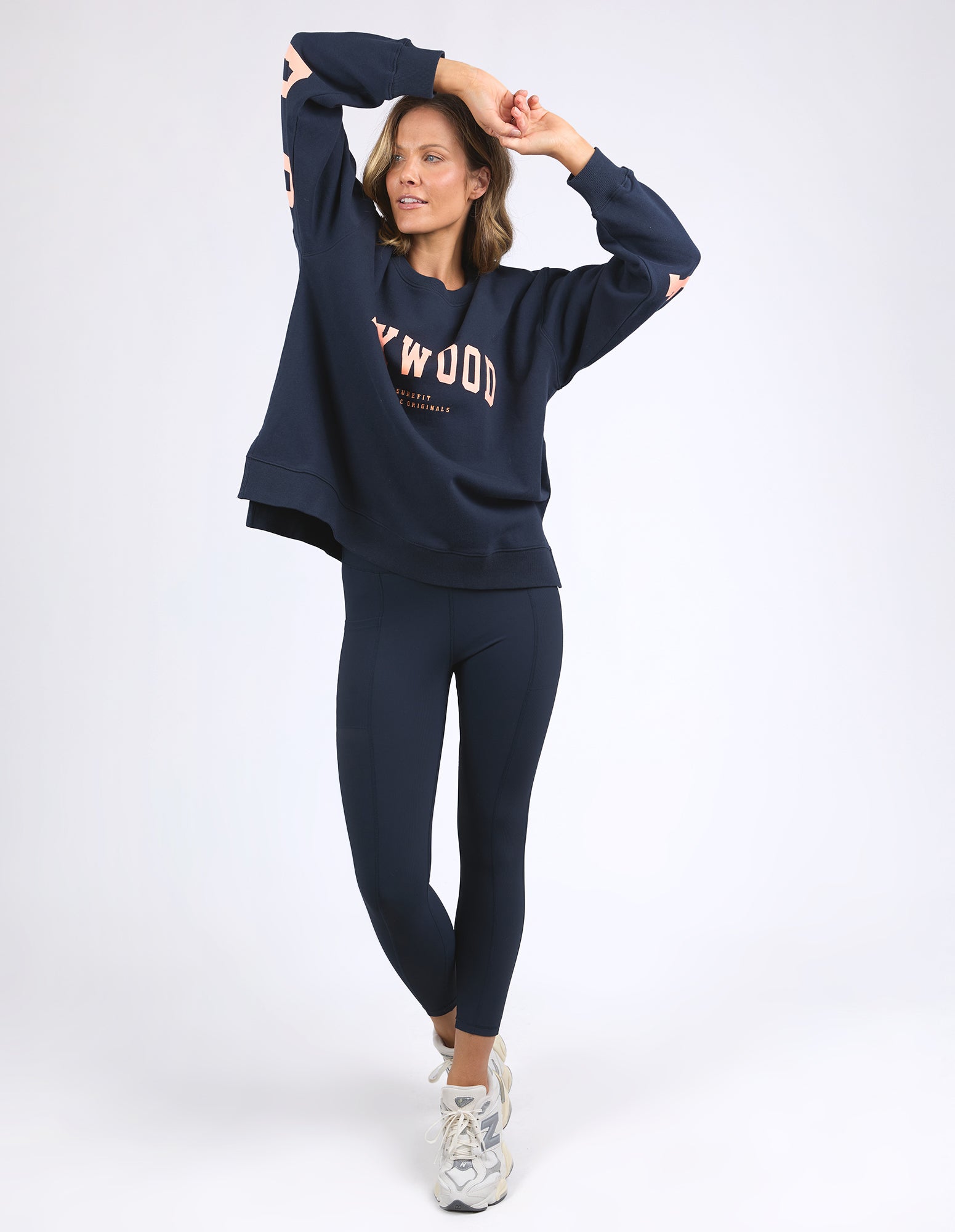 Image of Woman wearing a Foxwood navy blue sweatshirt and leggings with branding on a white background