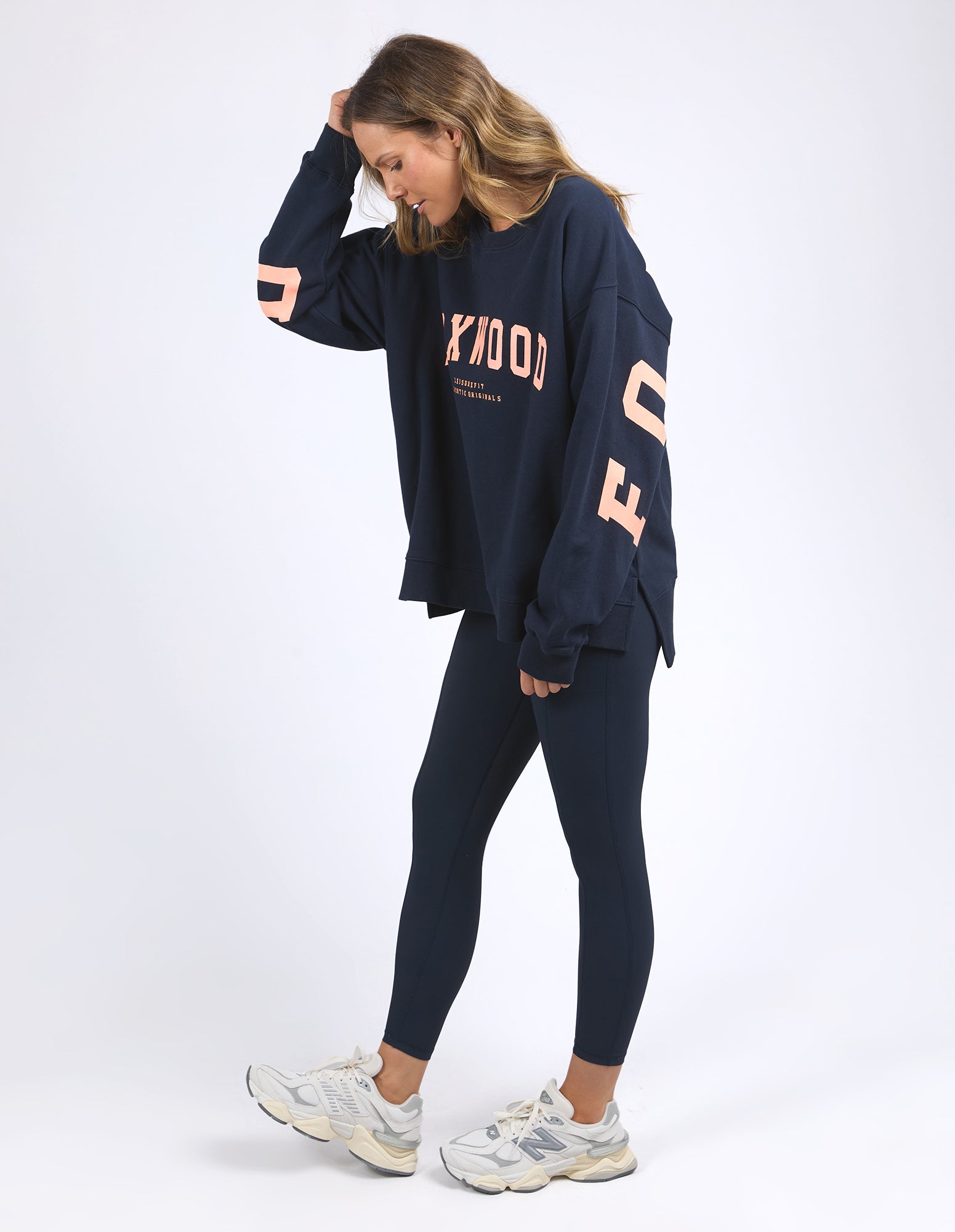 Image of Woman wearing a Foxwood navy sweatshirt and leggings with 'FOXWOOD' branding on a white background