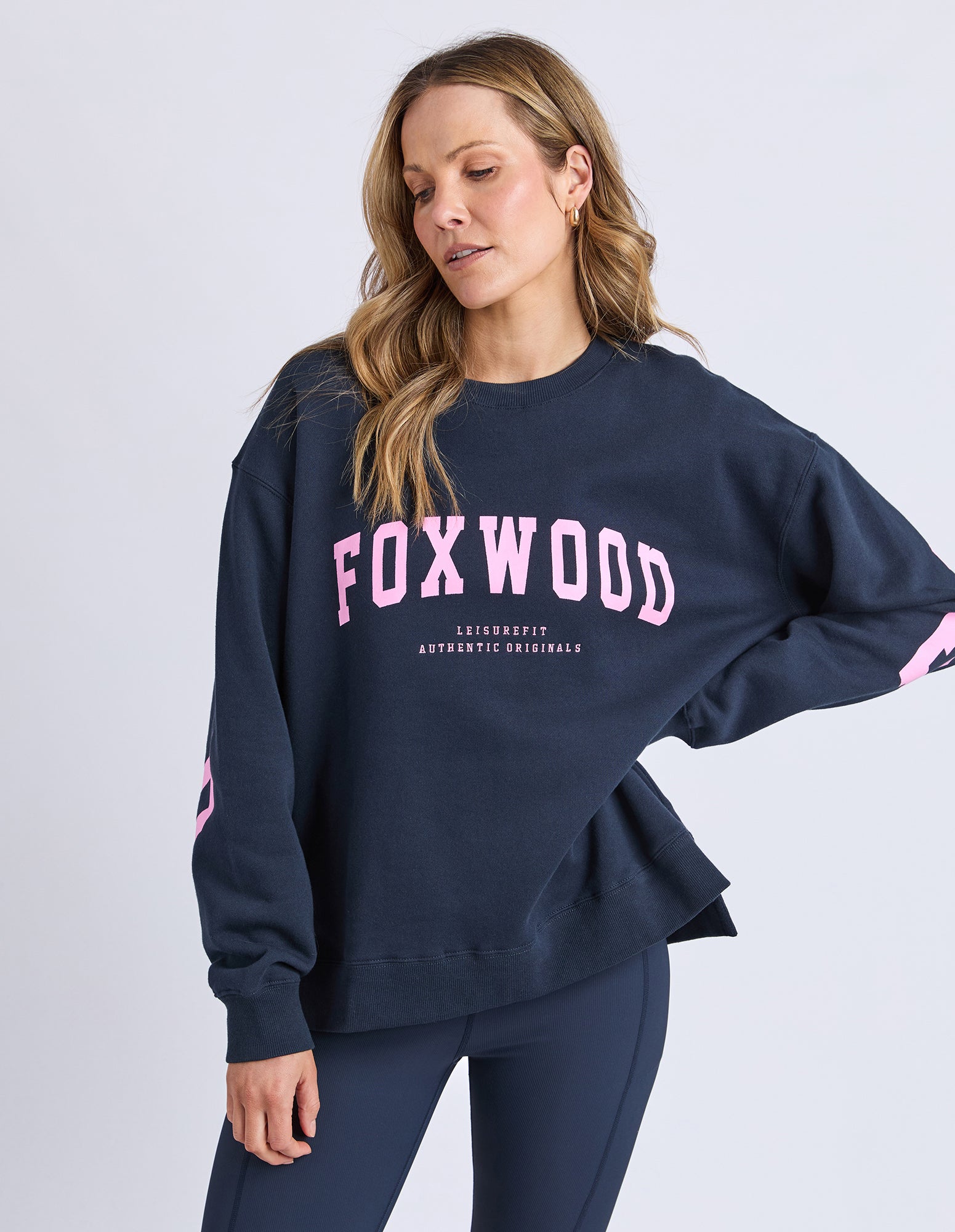 Woman wearing a navy sweatshirt with 'FOXWOOD' printed in pink on a light gray background