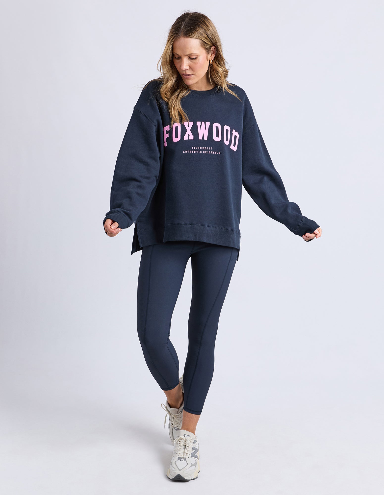 Image of Woman wearing a navy sweatshirt and leggings with 'FOXWOOD' branding on a white background
