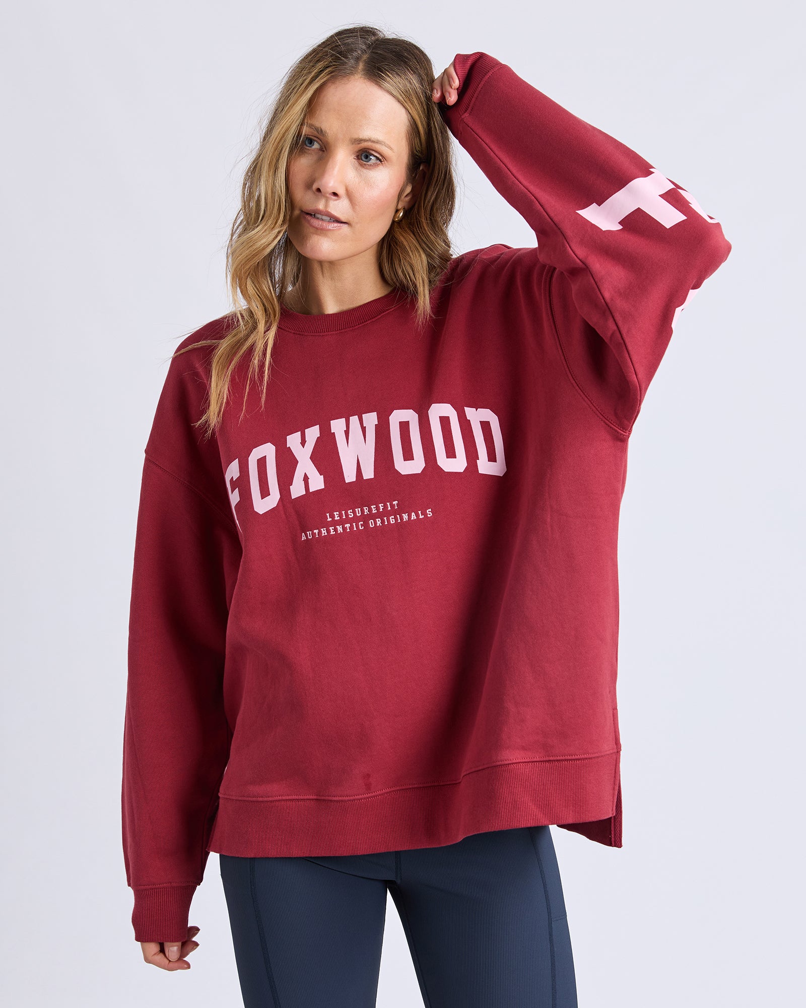 Image of Woman wearing a red 'FOXWOOD' sweatshirt on a light gray background